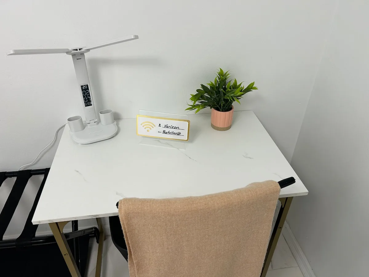 A small desk holds a lamp, a potted plant, and a Wi-Fi sign.