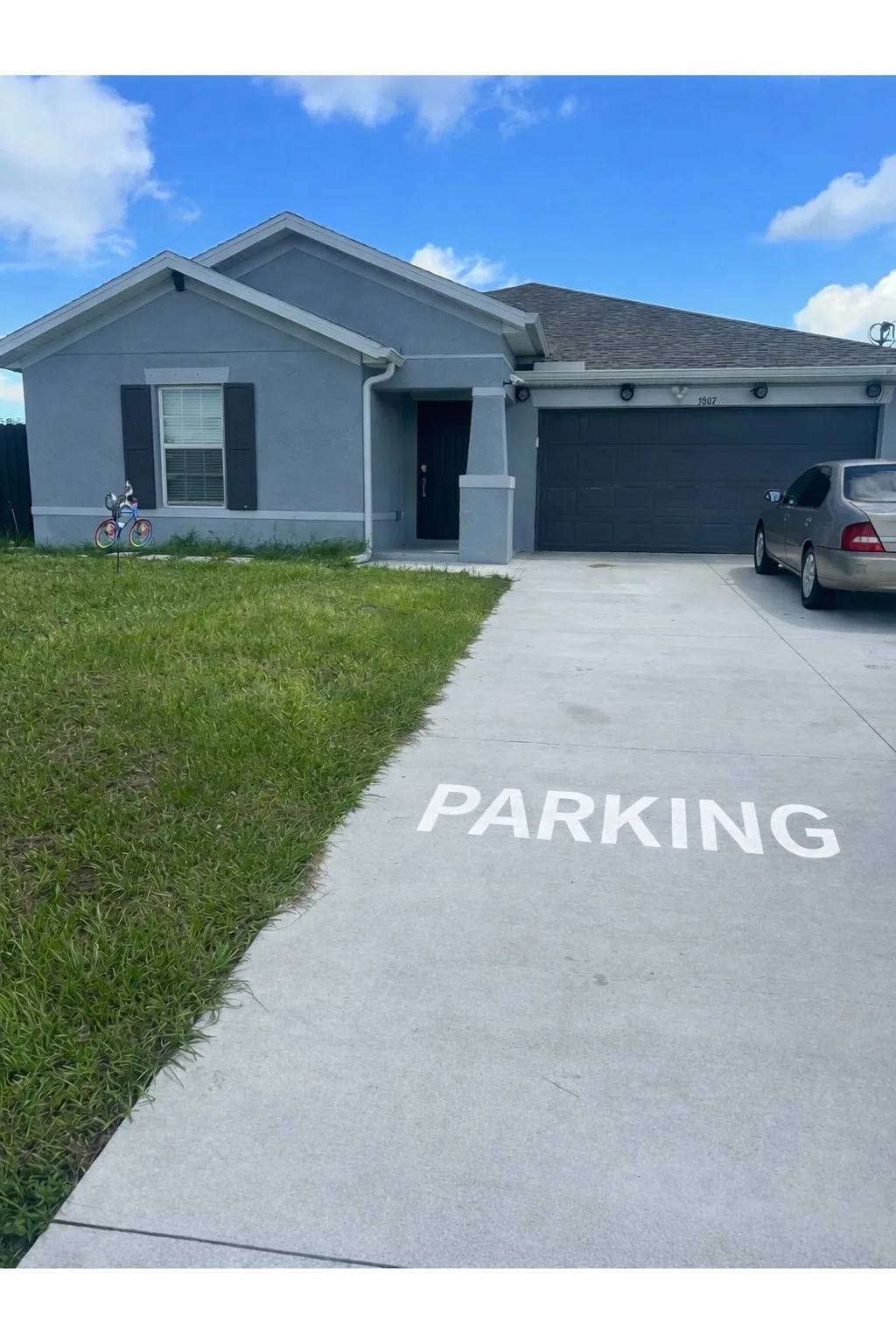 Shared amenity: A gray house with a driveway and a parked car.