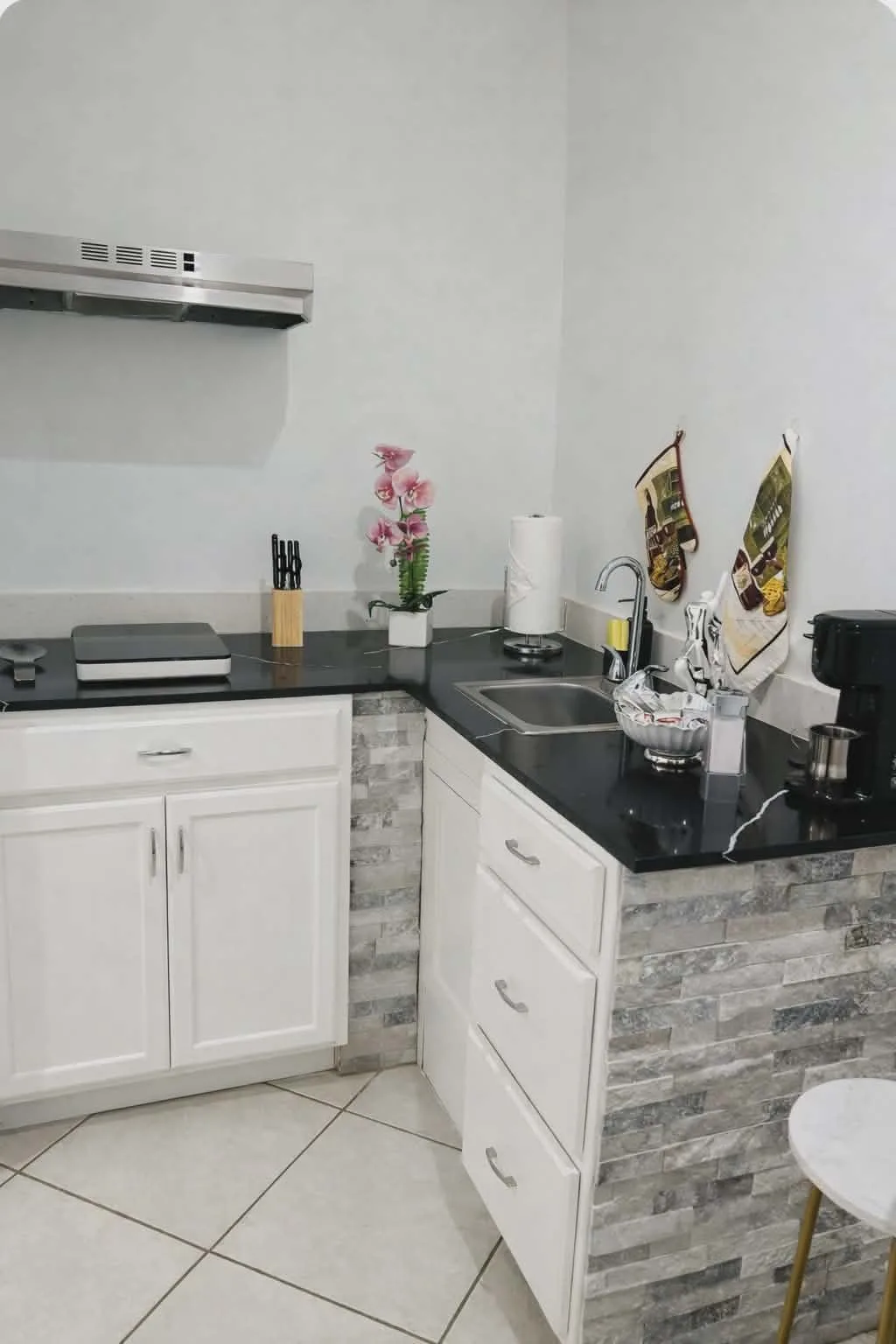 A compact kitchen with white cabinets, dark countertops, and a sink.
