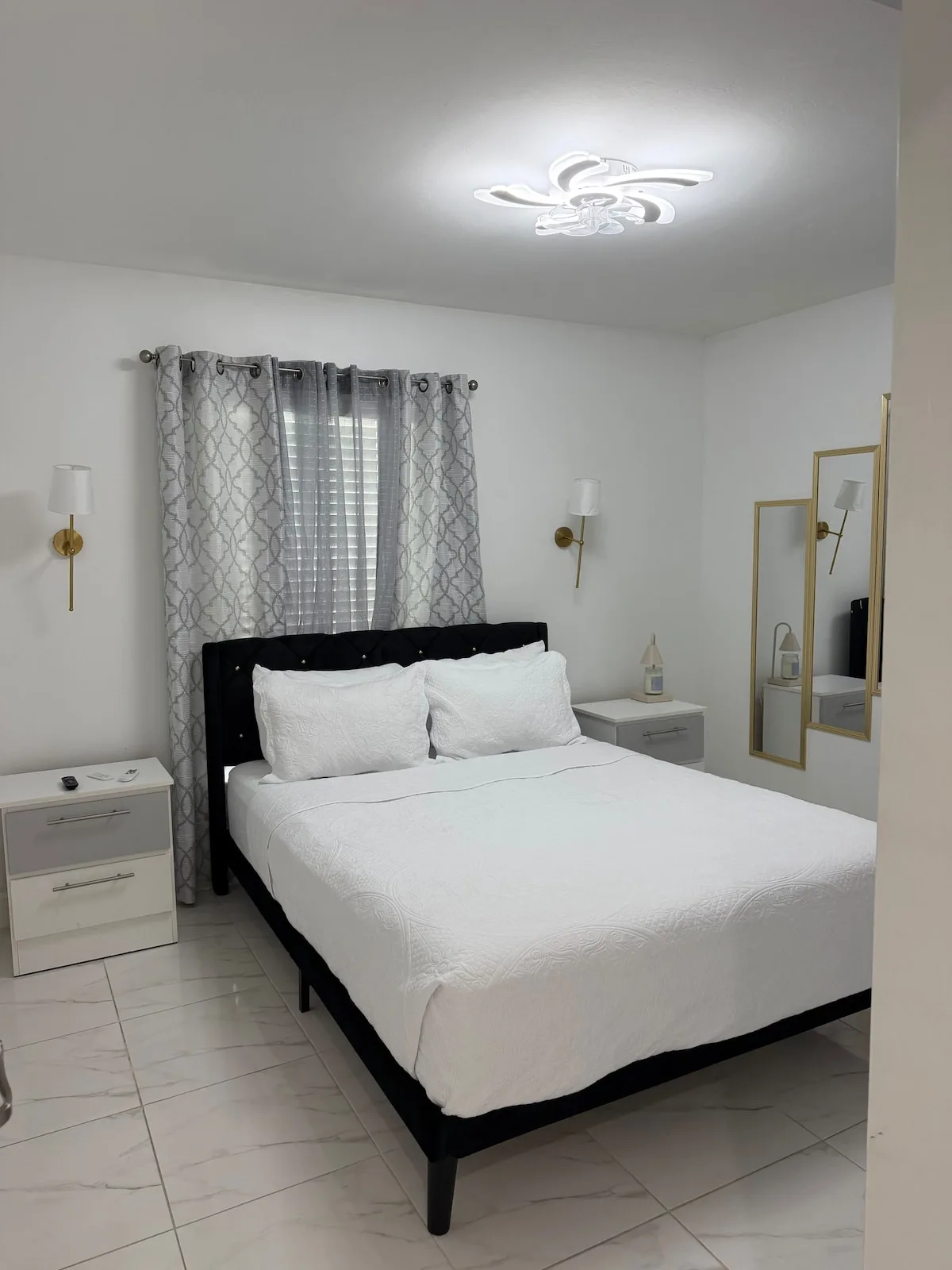 A bedroom with a neatly made bed and patterned curtains.