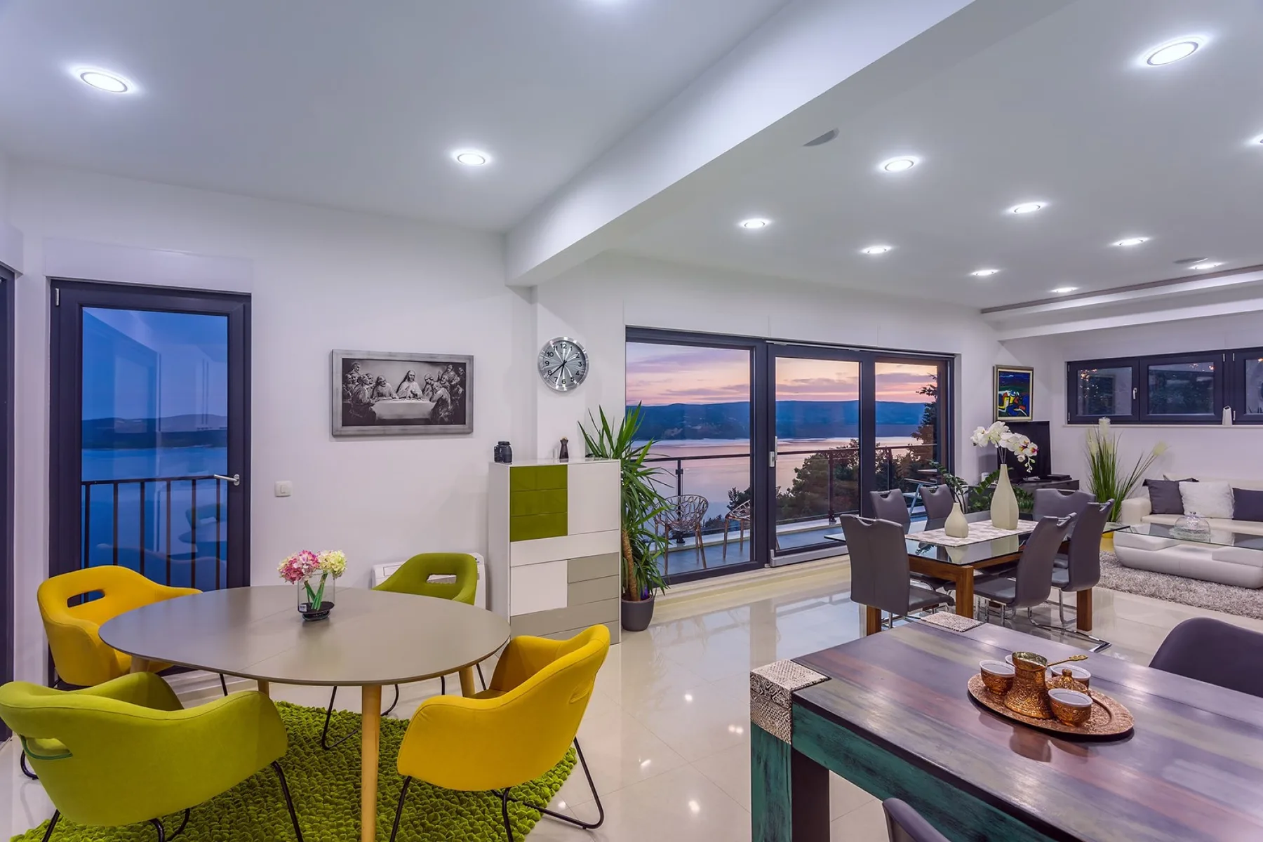 A bright open-plan living and dining area with large windows overlooking the water.