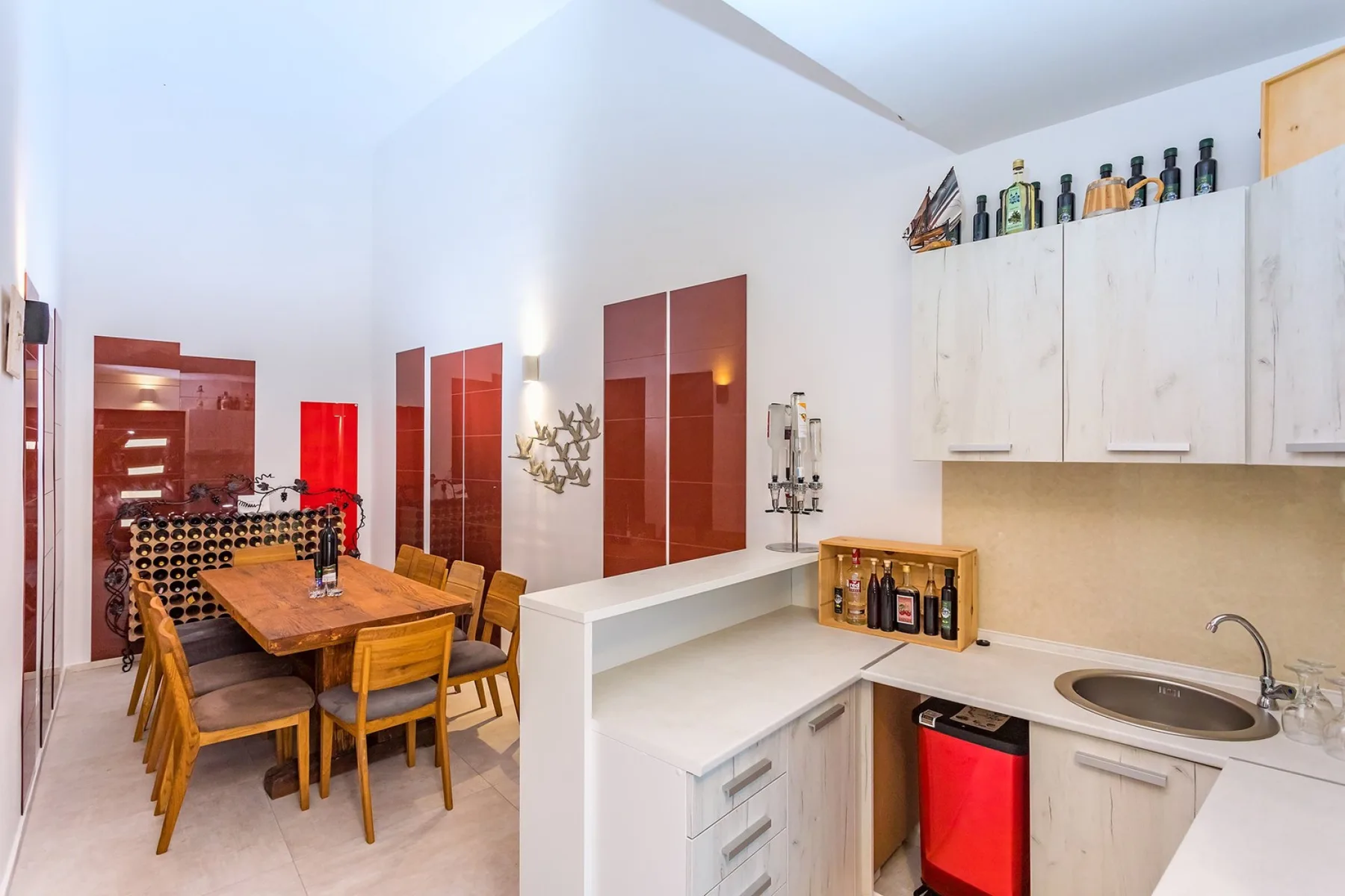 A bright kitchen and dining area with a wooden table beside white cabinetry.