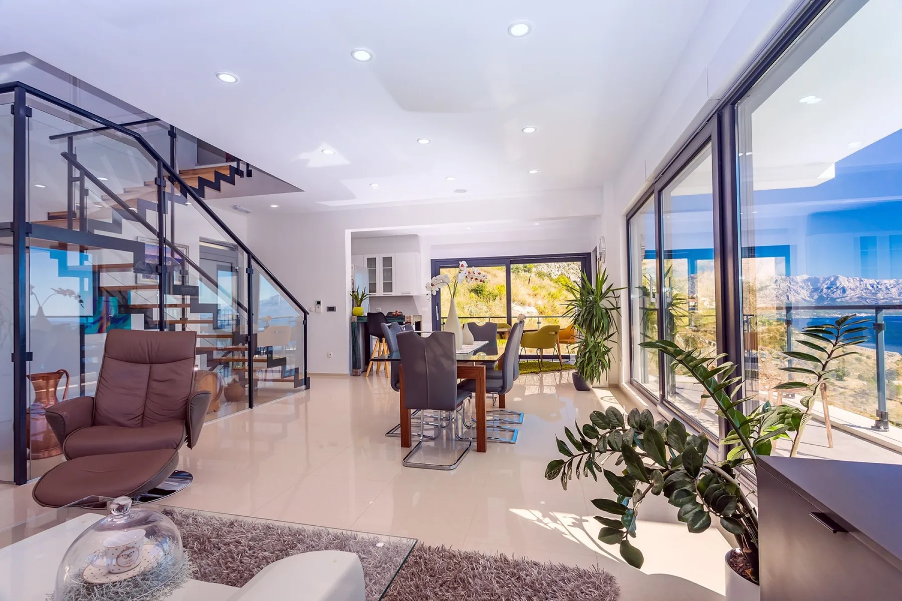 A bright open-plan living and dining area with glass doors and a staircase.
