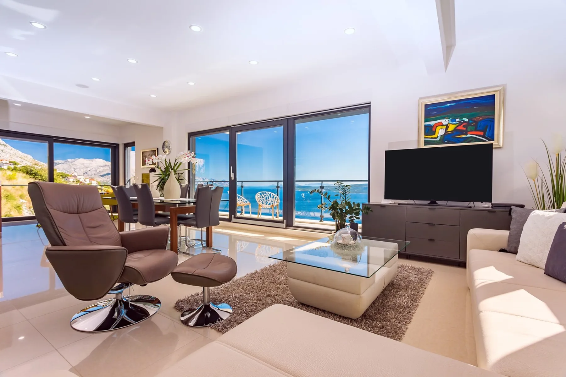 A bright living room opens onto a balcony with views of the sea.