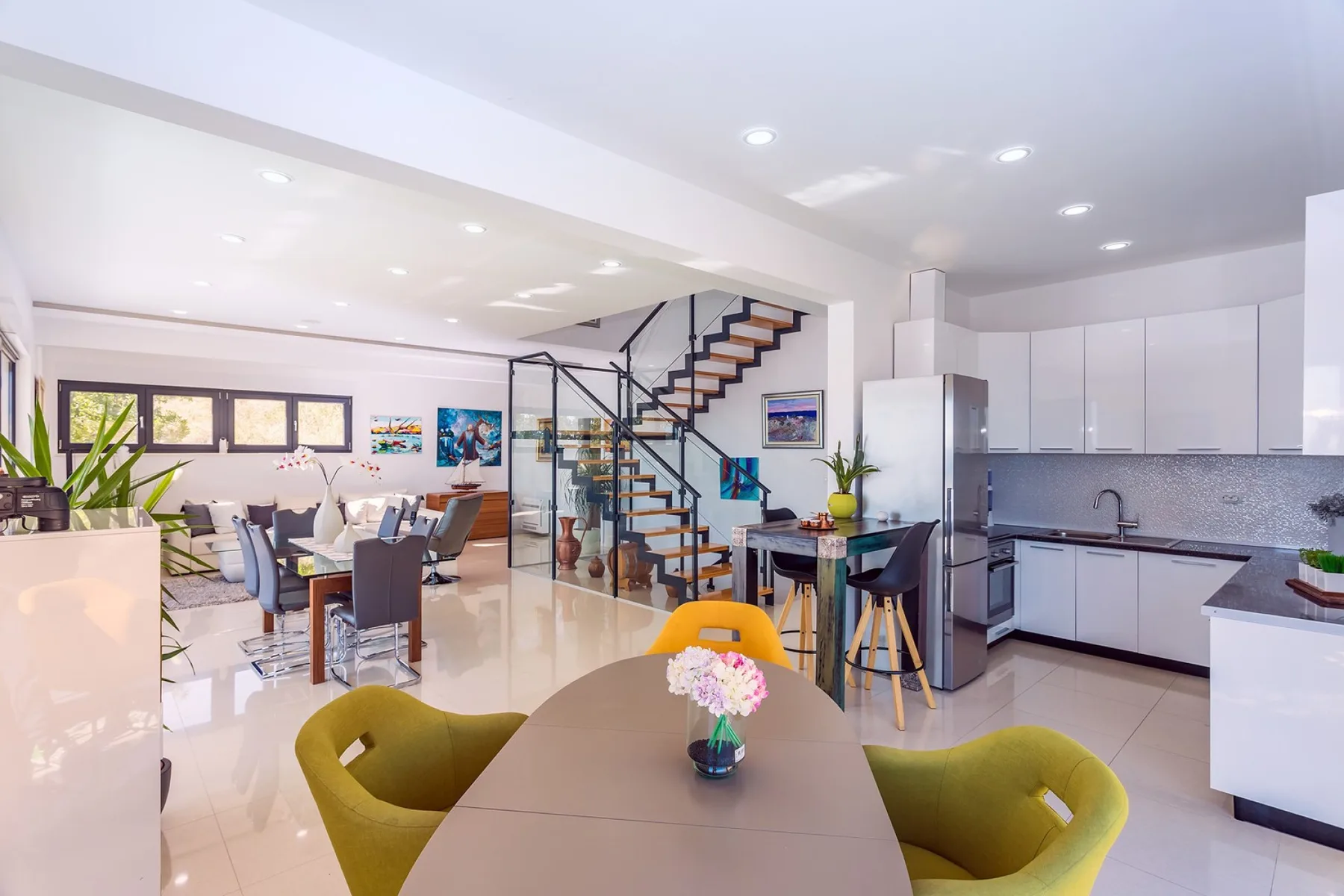 An open-plan dining area, living room, and kitchen share a bright interior.