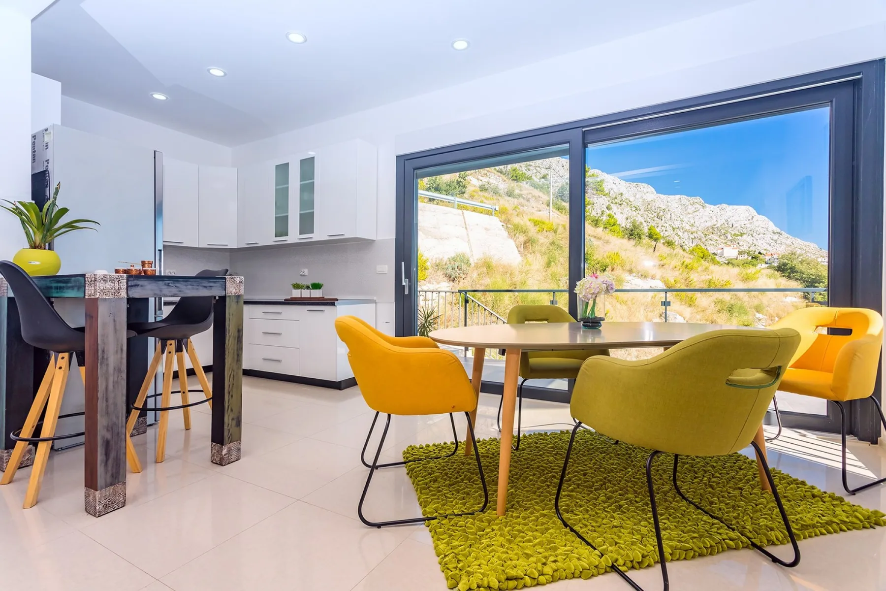 A bright dining area with colorful seating beside large windows.