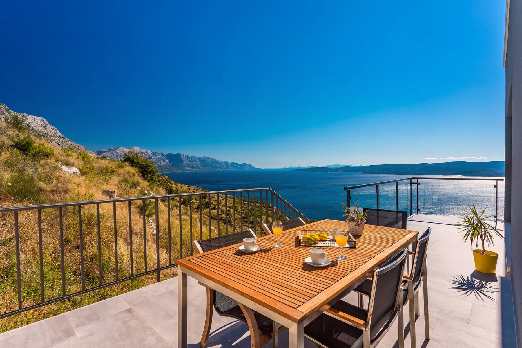 A terrace dining area overlooks the sea, with a table and outdoor seating.