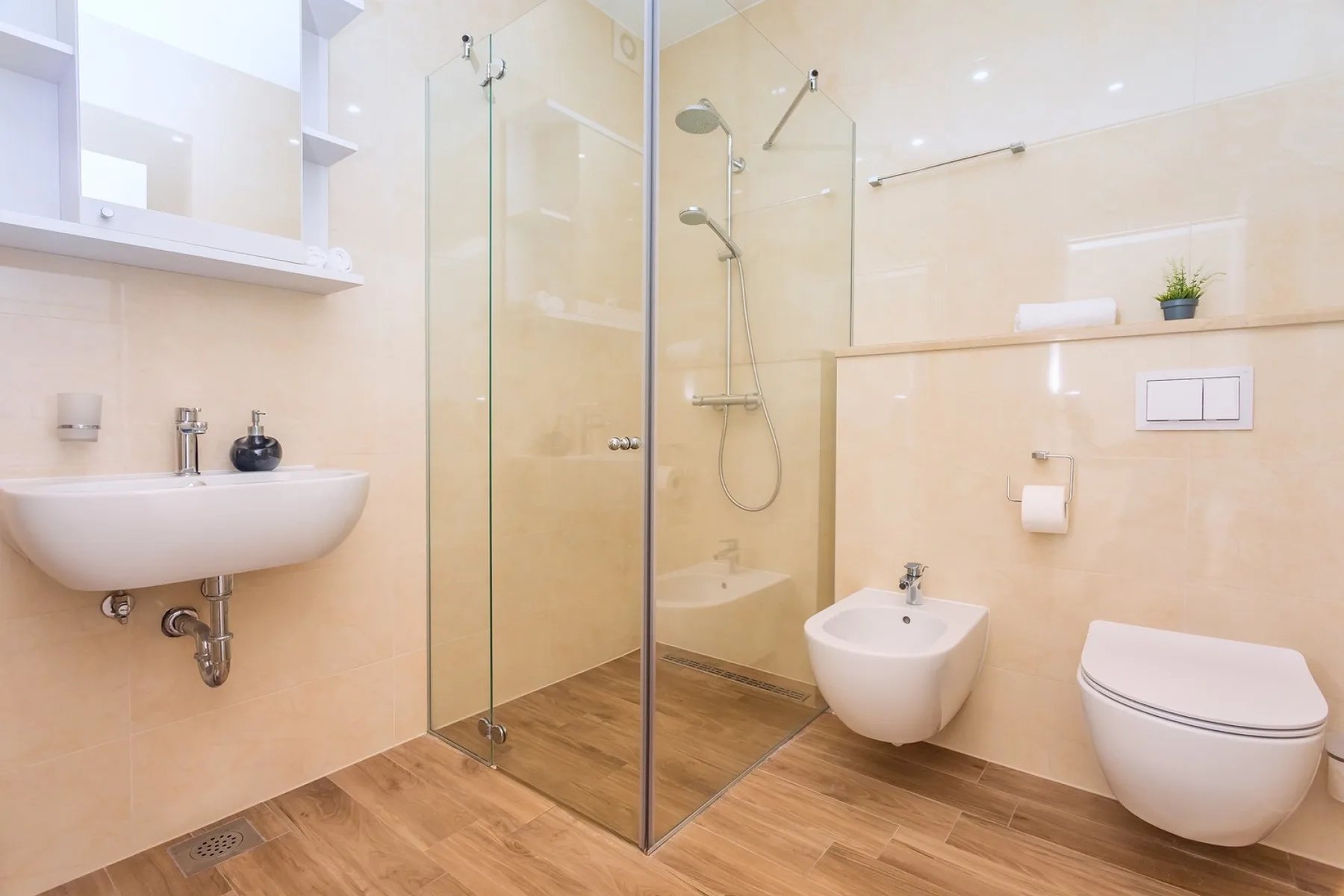 A bright bathroom with a glass shower, sink, and toilet.
