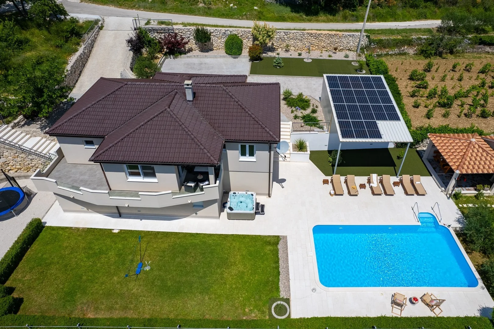 Aerial view of a house, swimming pool, and landscaped yard.