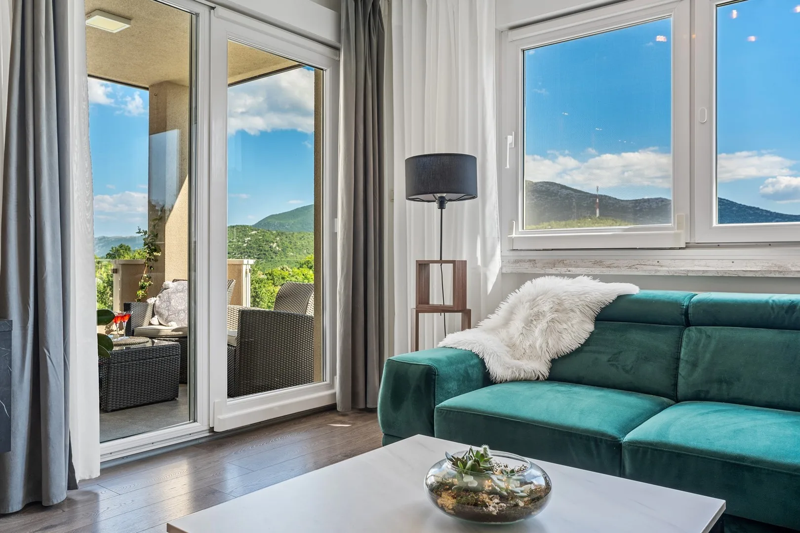 Living room with teal seating beside glass doors opening onto a patio.