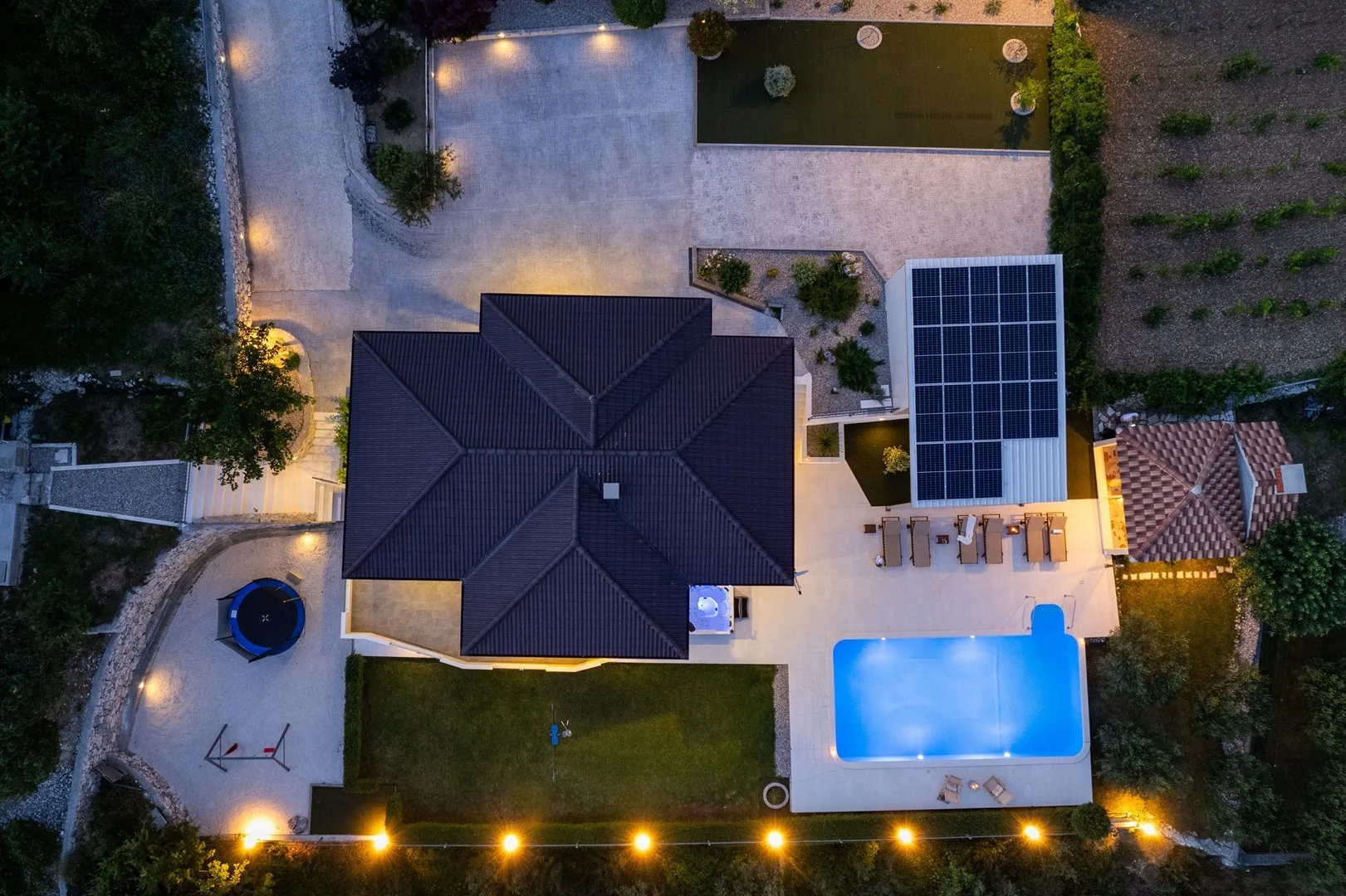 An aerial view shows a house, swimming pool, and solar panels.