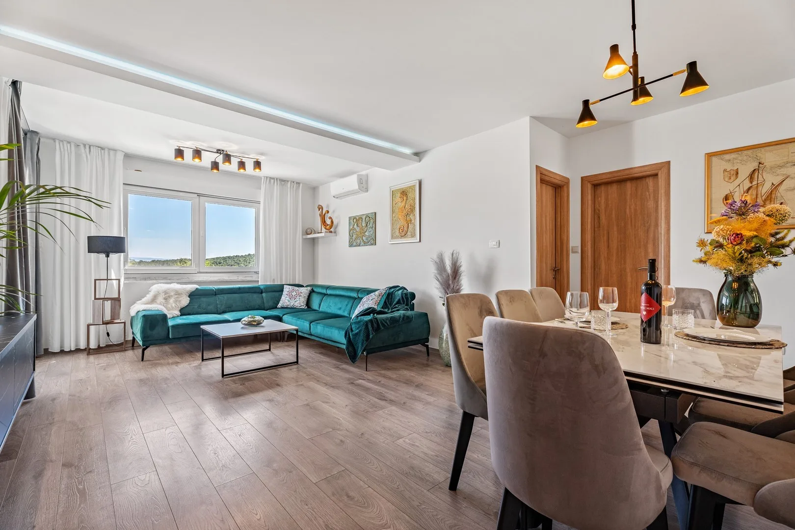A bright living and dining area with teal seating and a set dining table.