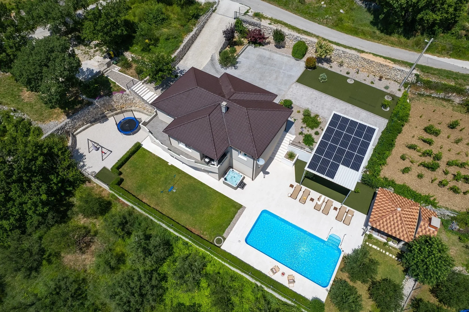 An aerial view of a house with a swimming pool and solar panels.