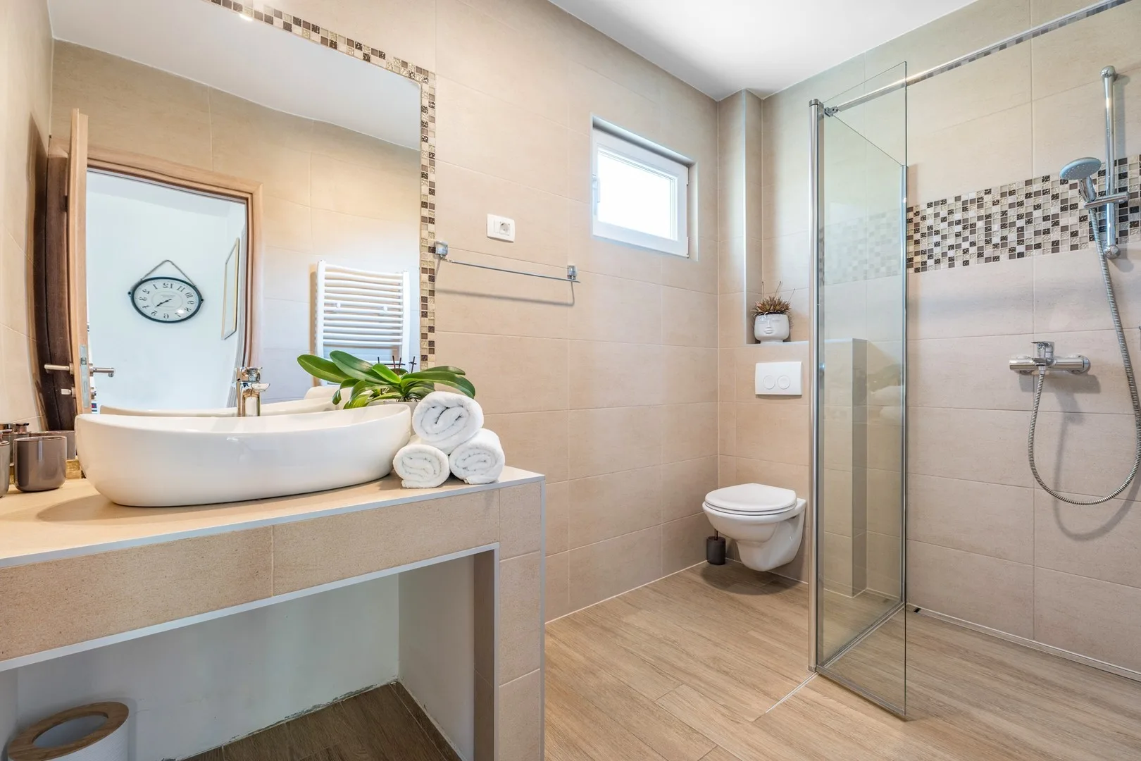 A bathroom with a vessel sink, toilet, and glass shower.