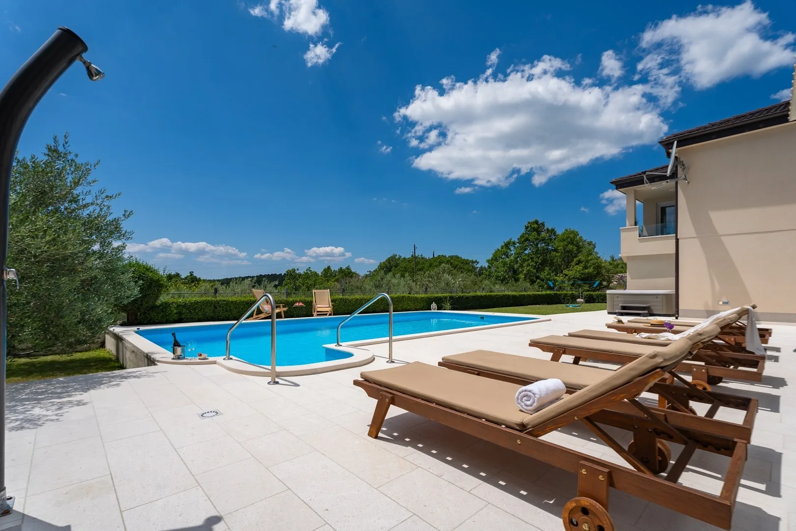 An outdoor swimming pool beside a paved deck with loungers.