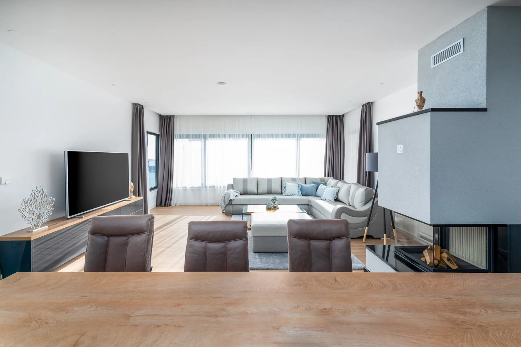 A bright living room with a sectional sofa, coffee table, television, and fireplace.