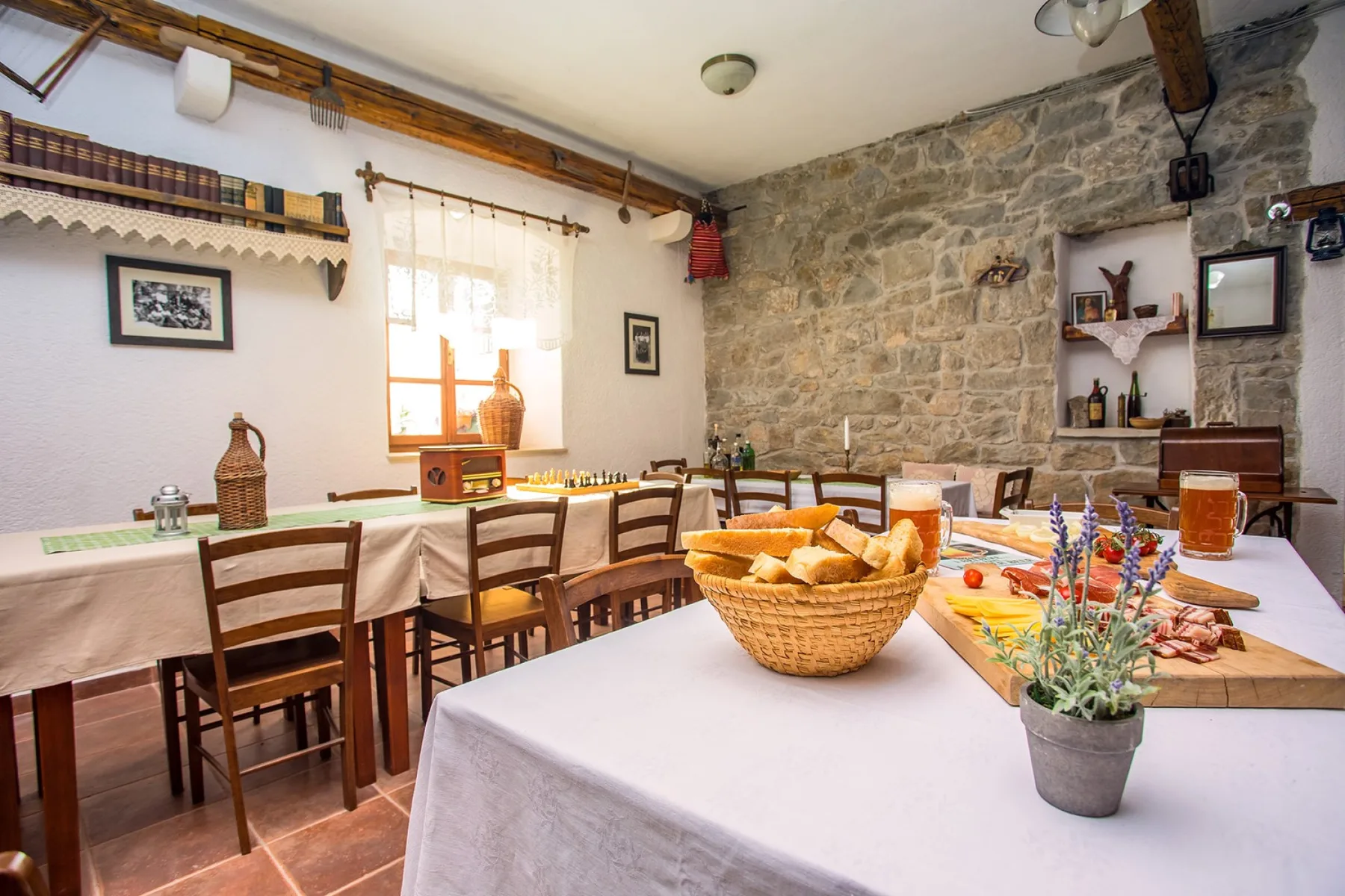 Zona común: Un comedor con mesas preparadas para comer y una pared de piedra.