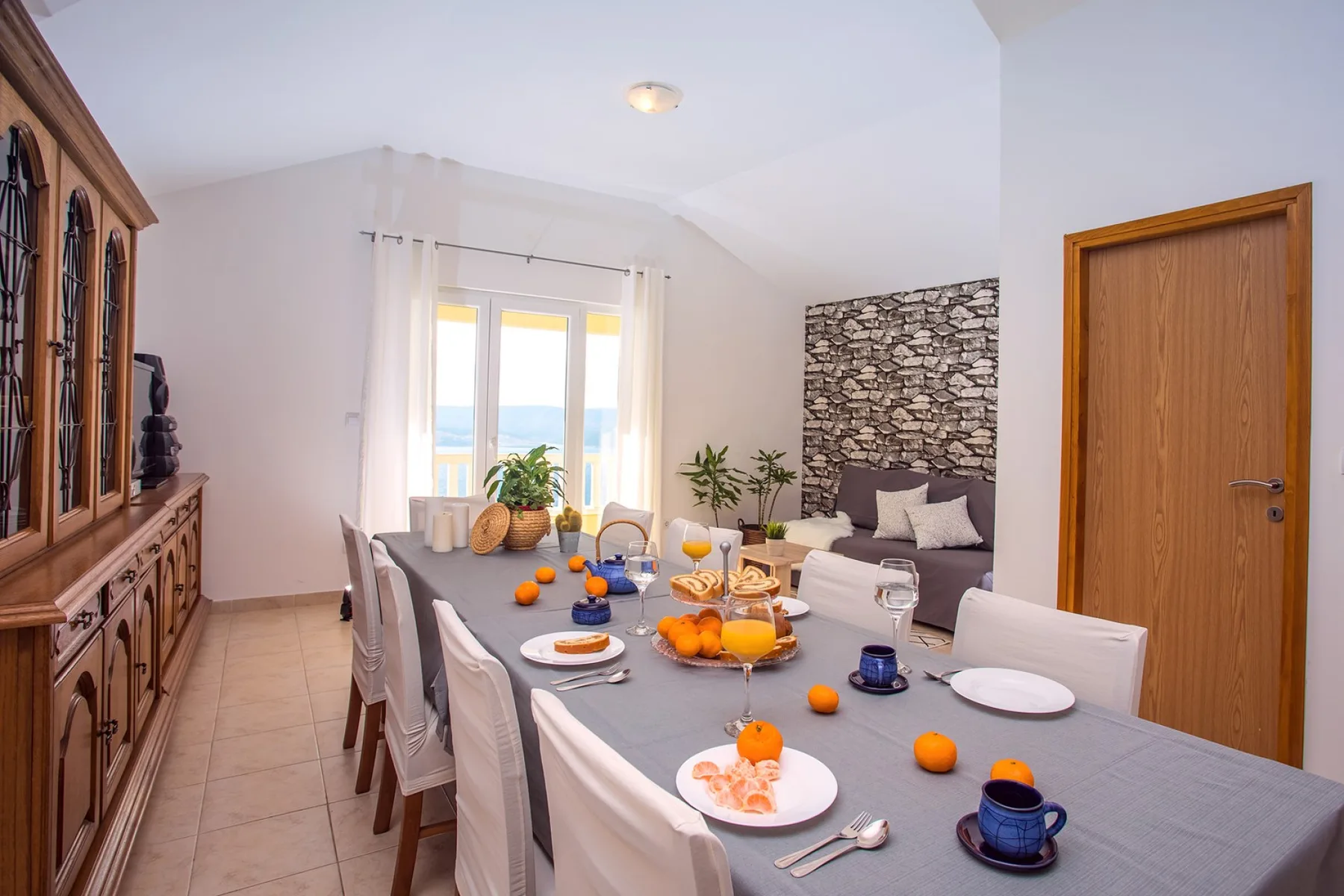Un comedor con una mesa larga preparada con platos y fruta.