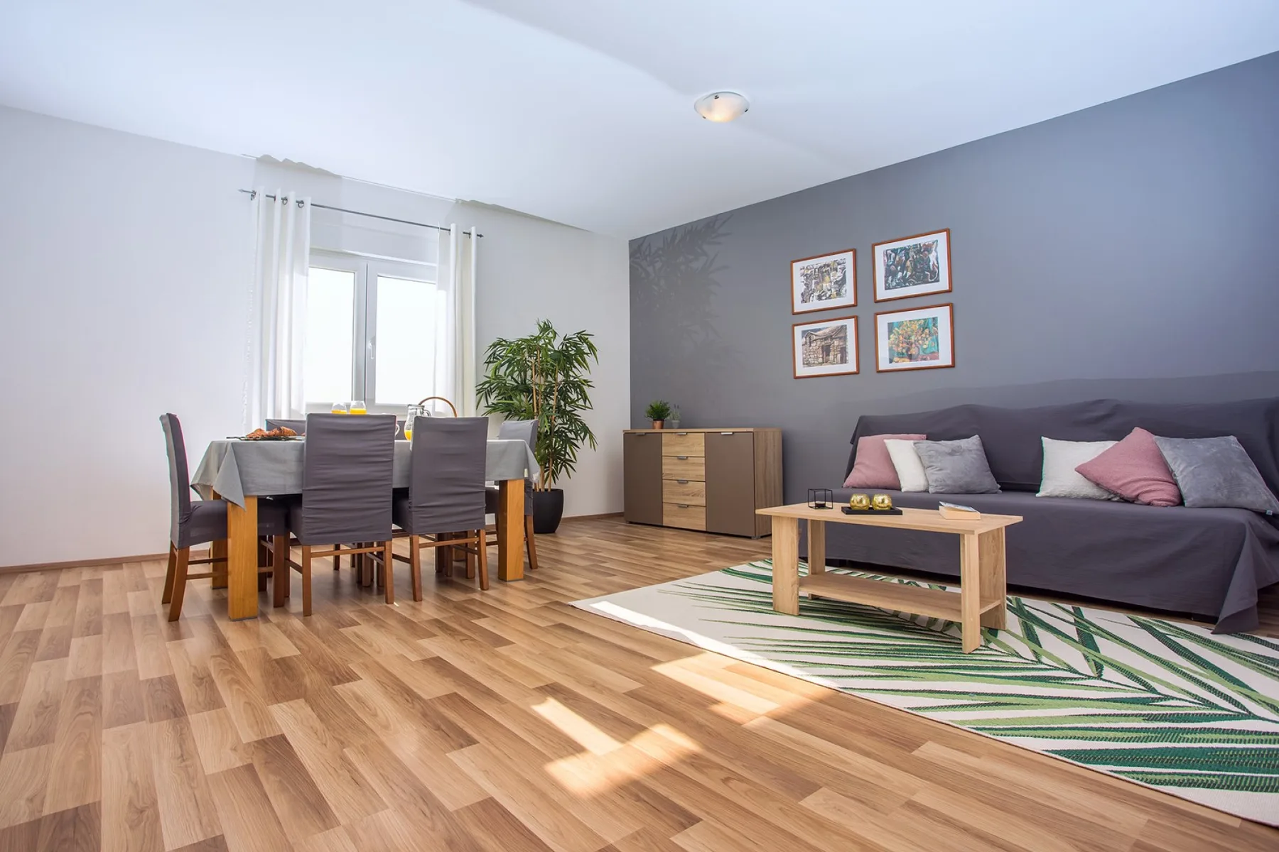 Sala de estar y comedor con sofá, mesa de comedor y suelo de madera.