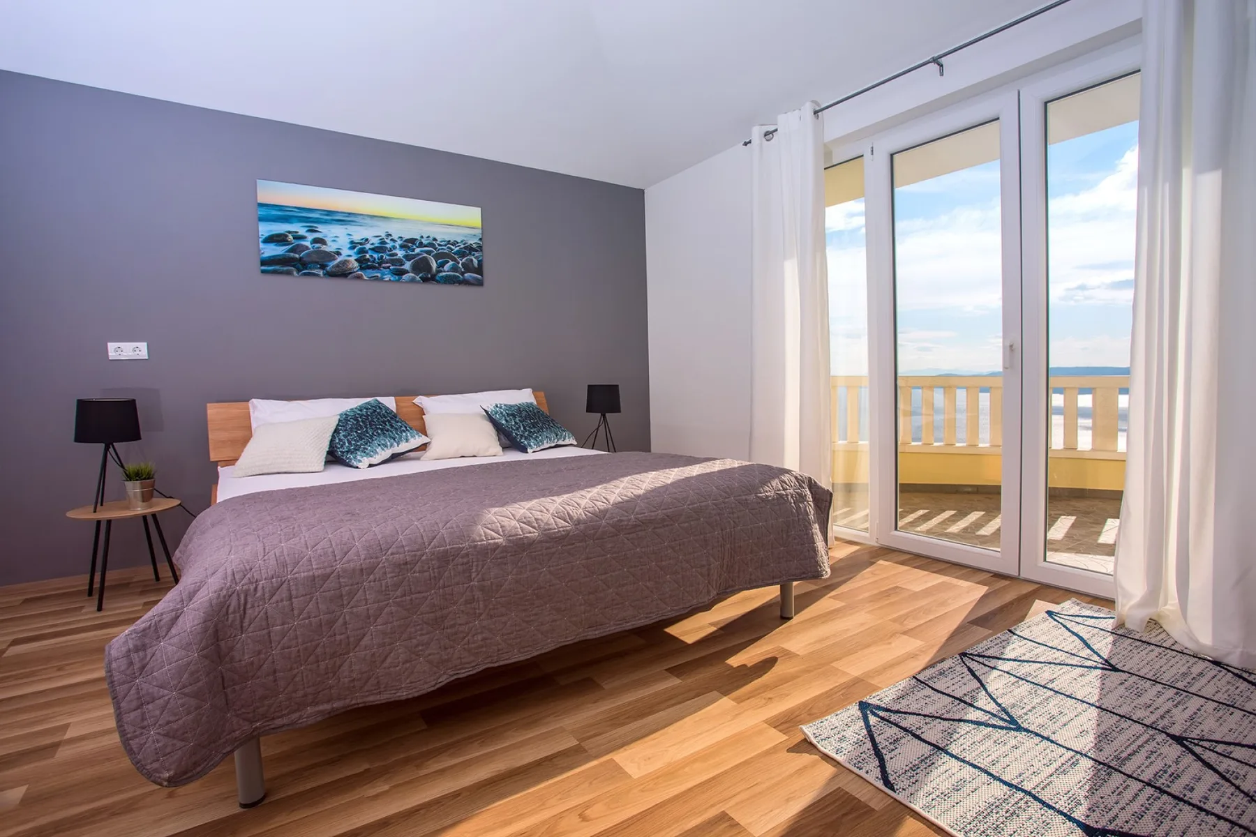 Un dormitorio con una cama junto a puertas de vidrio que dan a un balcón.