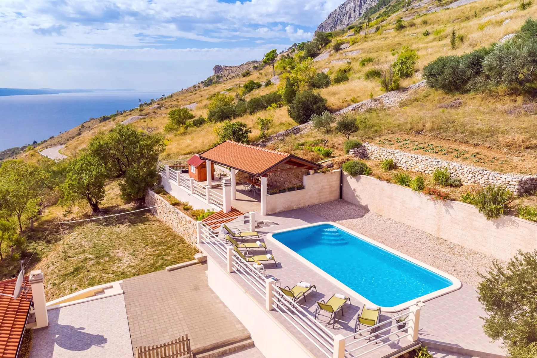 Una piscina exterior y un patio junto a un paisaje de ladera seca.
