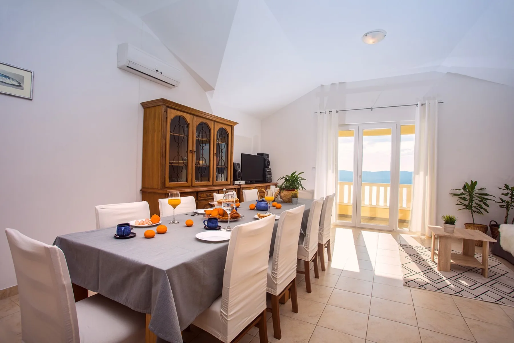 Comedor con una mesa preparada junto a puertas de cristal que dan a un balcón.