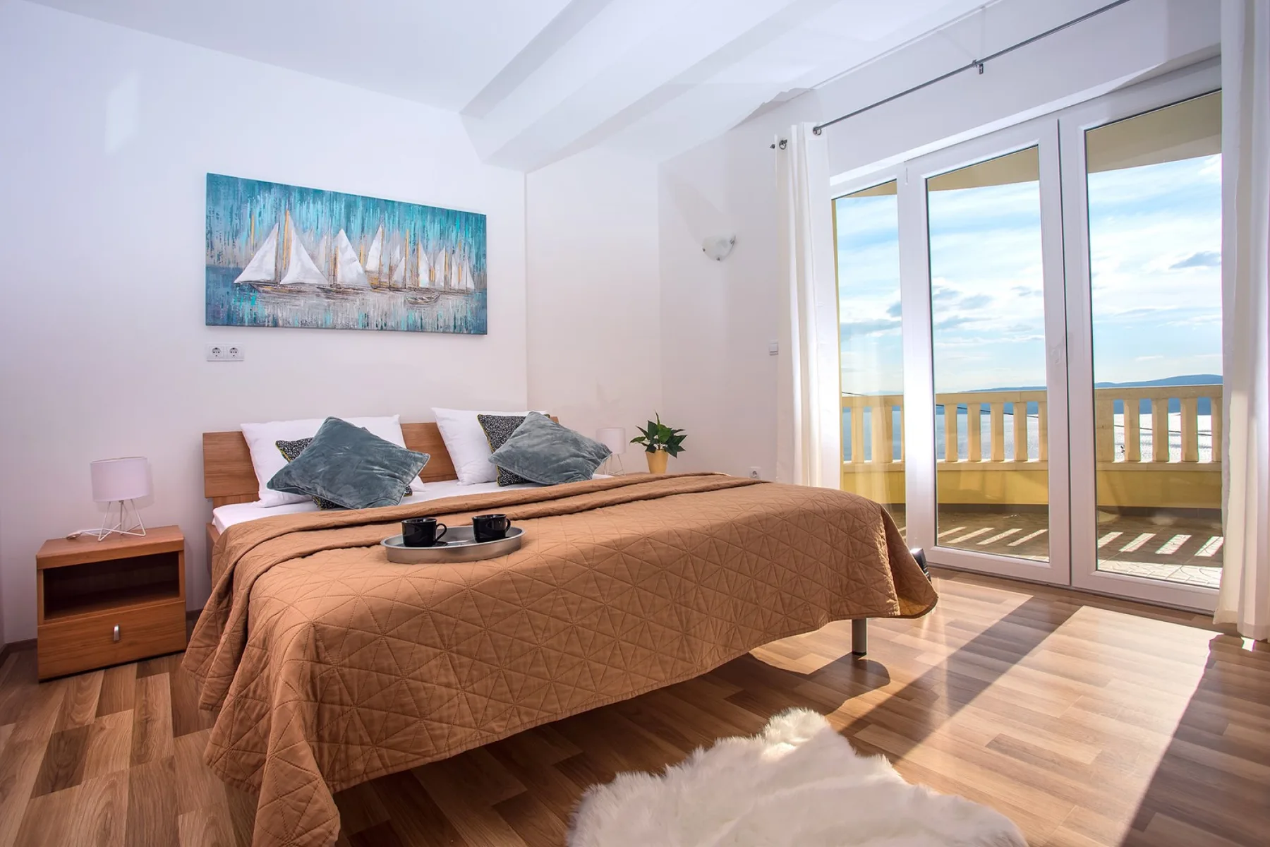 Un dormitorio con una cama tendida junto a puertas acristaladas que dan a un balcón.