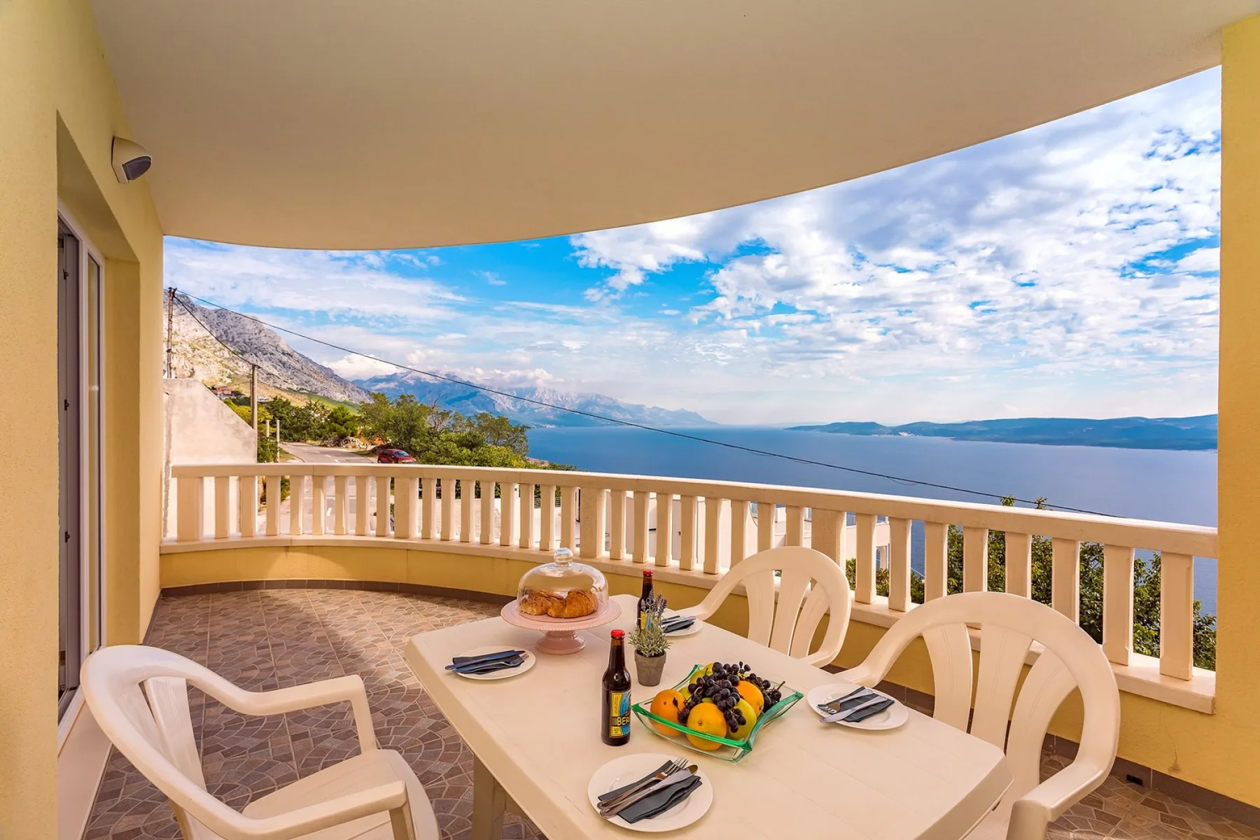 Una zona de comedor en un balcón cubierto da al mar, con mesa y sillas.