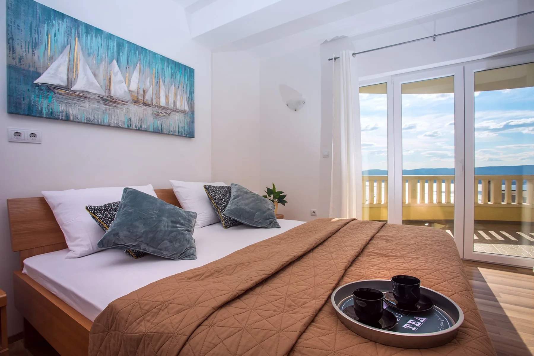 Un dormitorio con una cama junto a puertas de cristal que dan a un balcón.