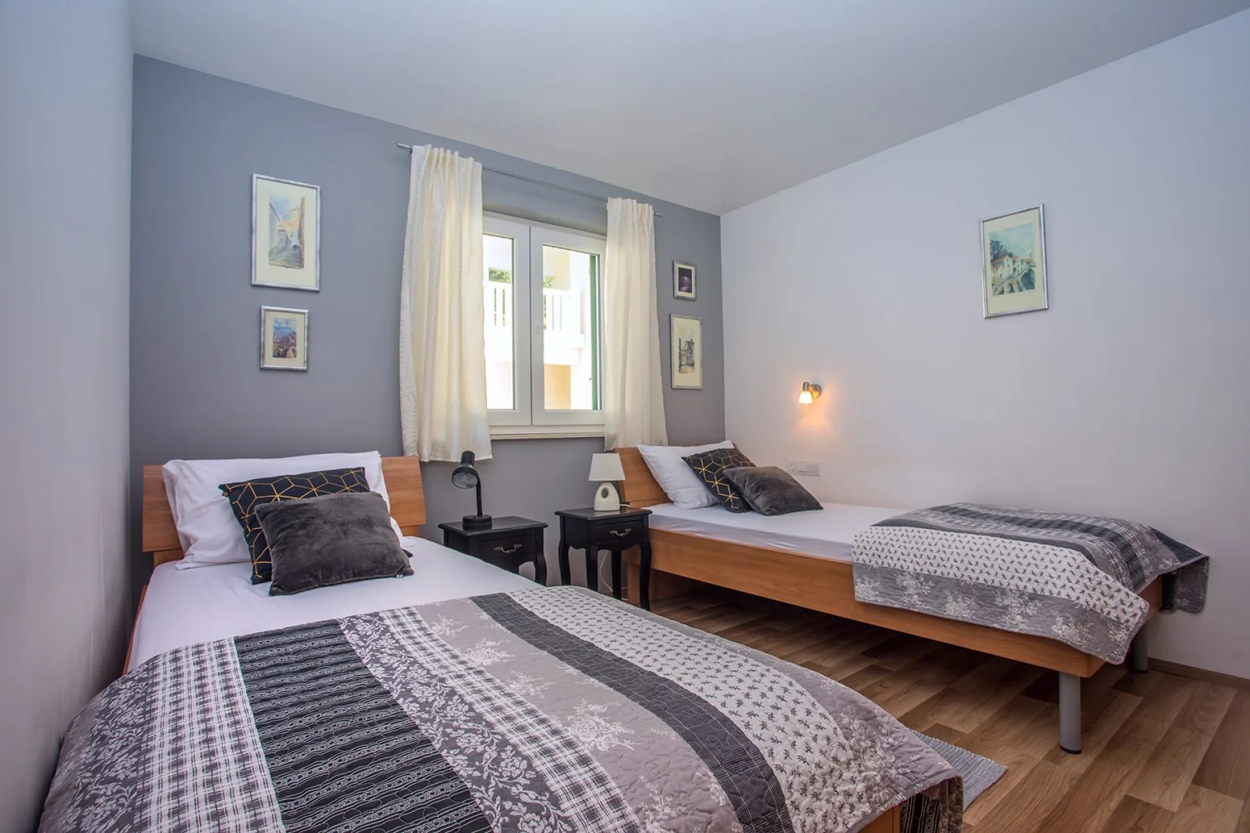 Un dormitorio con dos camas, ropa de cama estampada y una ventana entre ellas.