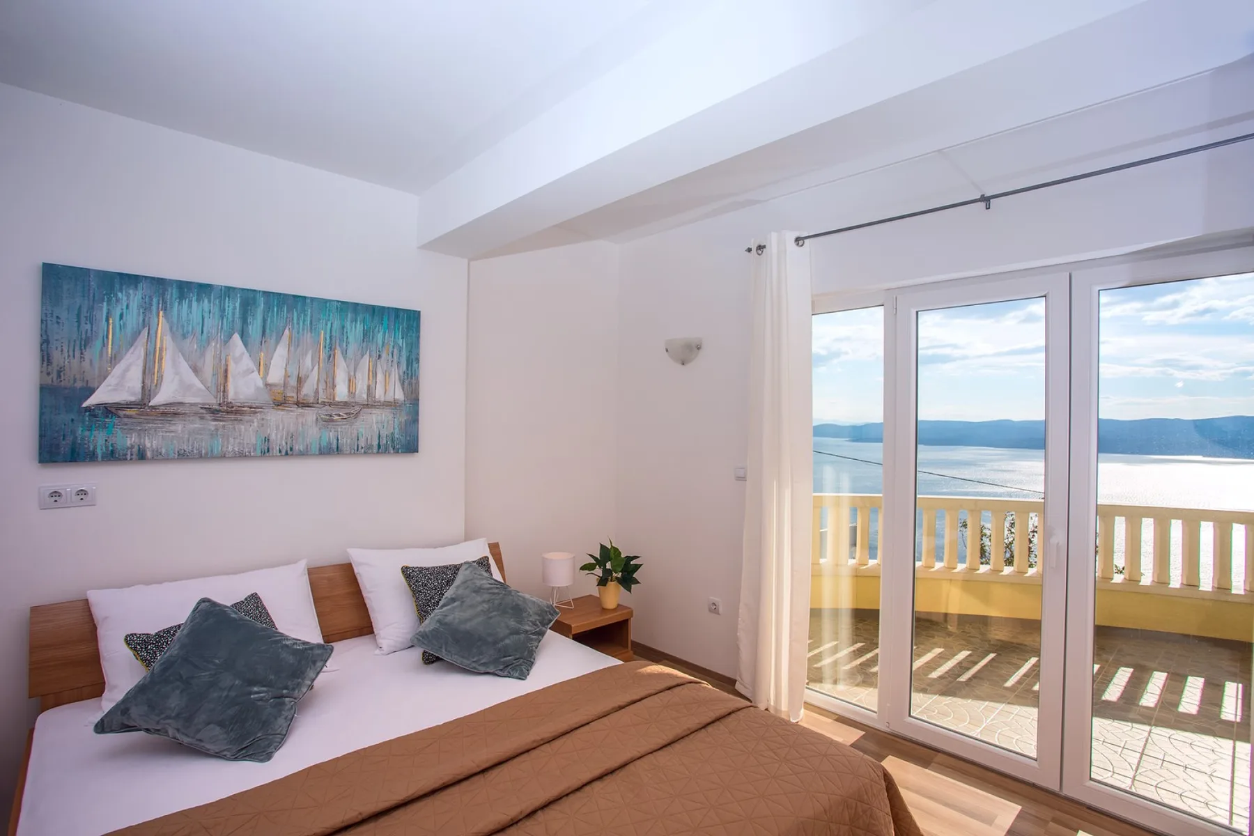 Un dormitorio luminoso con una cama junto a puertas de vidrio que dan a un balcón.