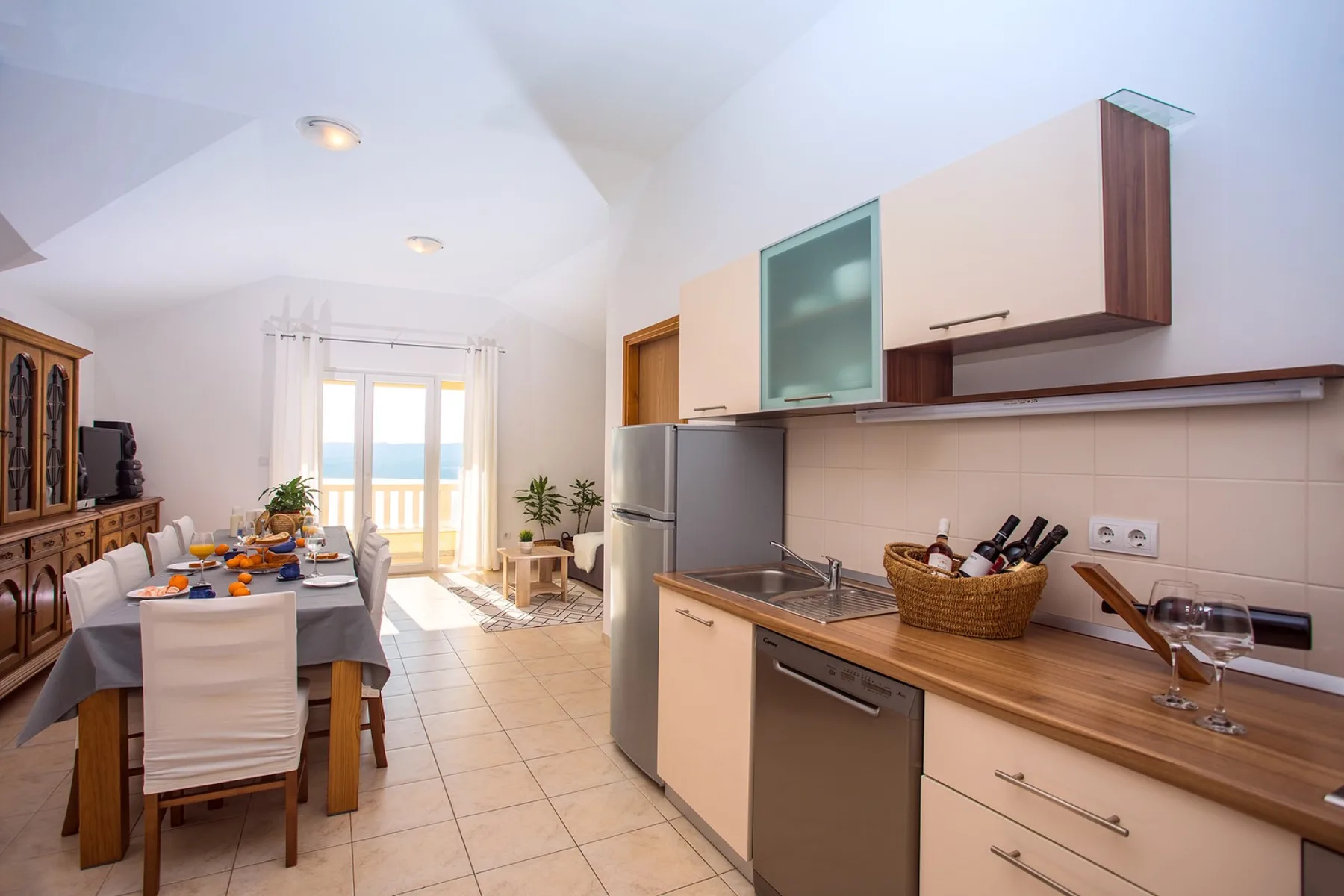 Una cocina y comedor con una mesa junto a ventanas luminosas.