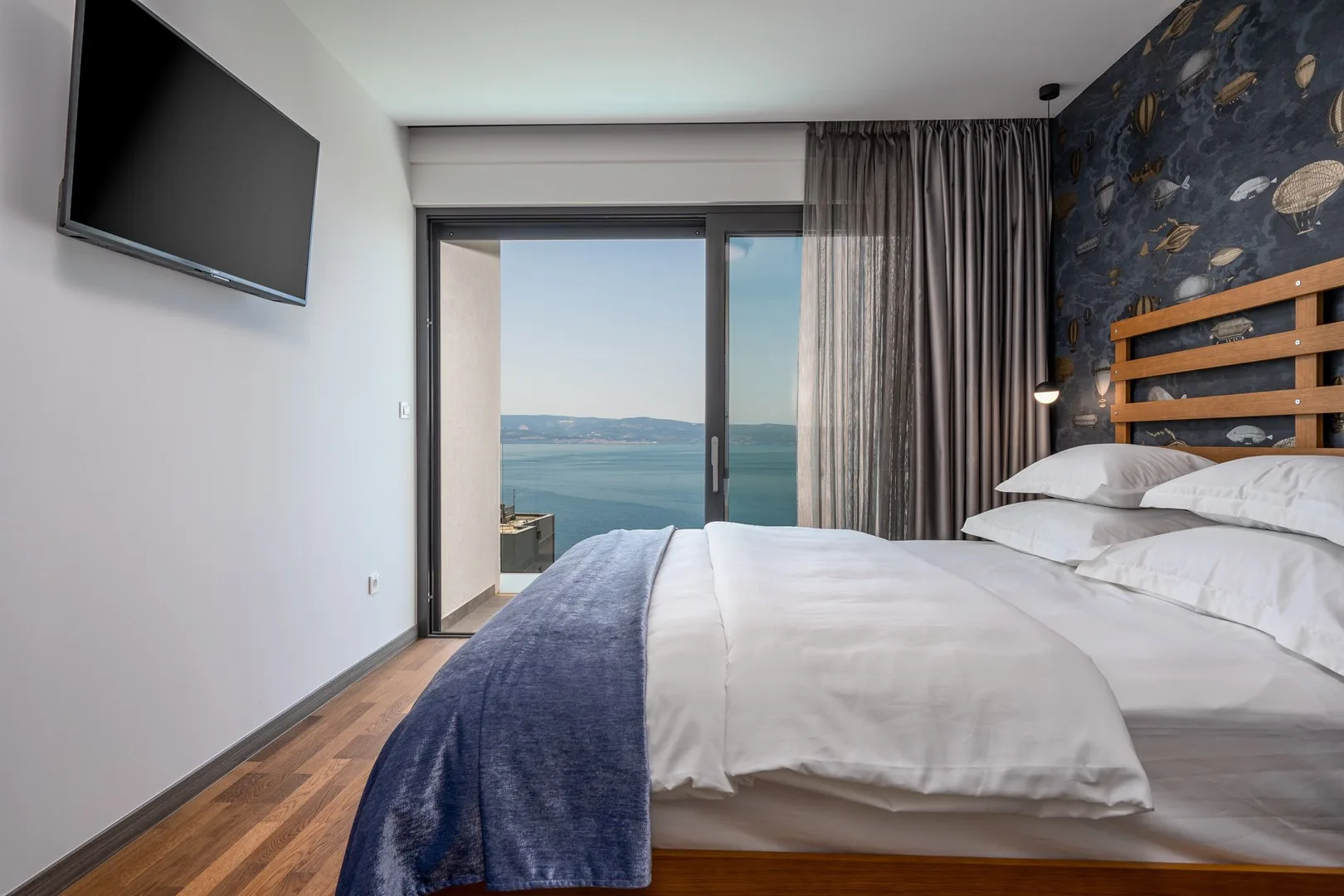 A bedroom with a bed beside sliding glass doors overlooking the water.