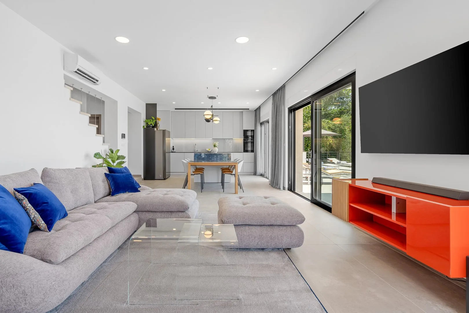 A bright open-plan living room with a sectional seating area and dining space.