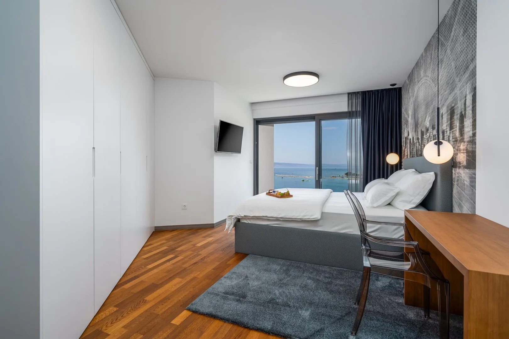 Bedroom with a bed facing glass doors that open onto a sea view.