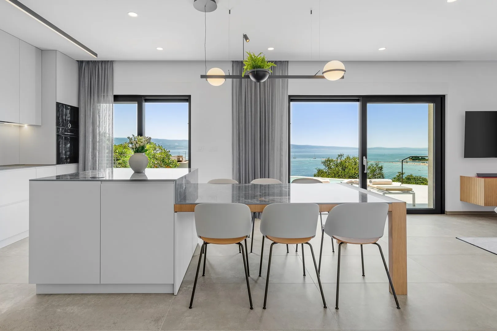 A bright open-plan kitchen and dining area overlooks the sea through large windows.