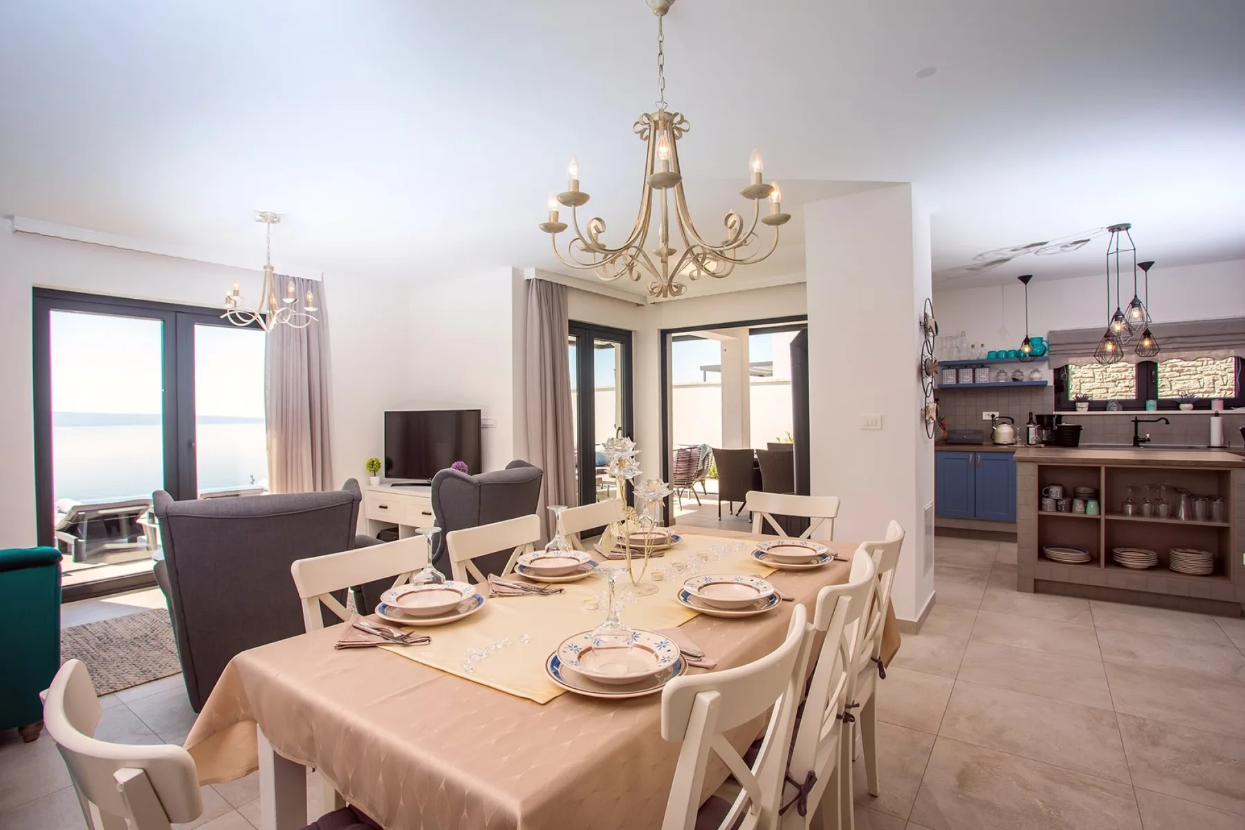 A dining area with a set table opens onto a bright living space and kitchen.