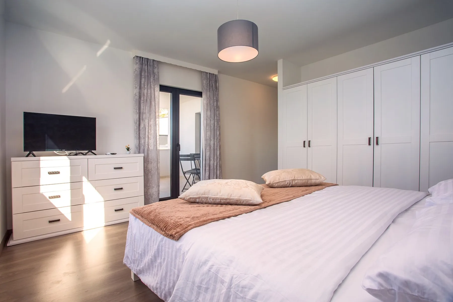 A bedroom with a large bed, built-in wardrobes, and a television on a dresser.