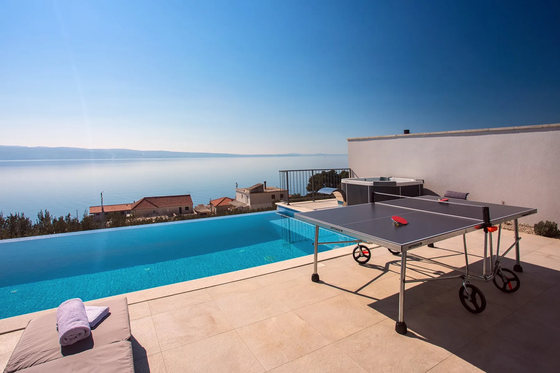 A rooftop terrace with a swimming pool and table tennis table overlooking the water.