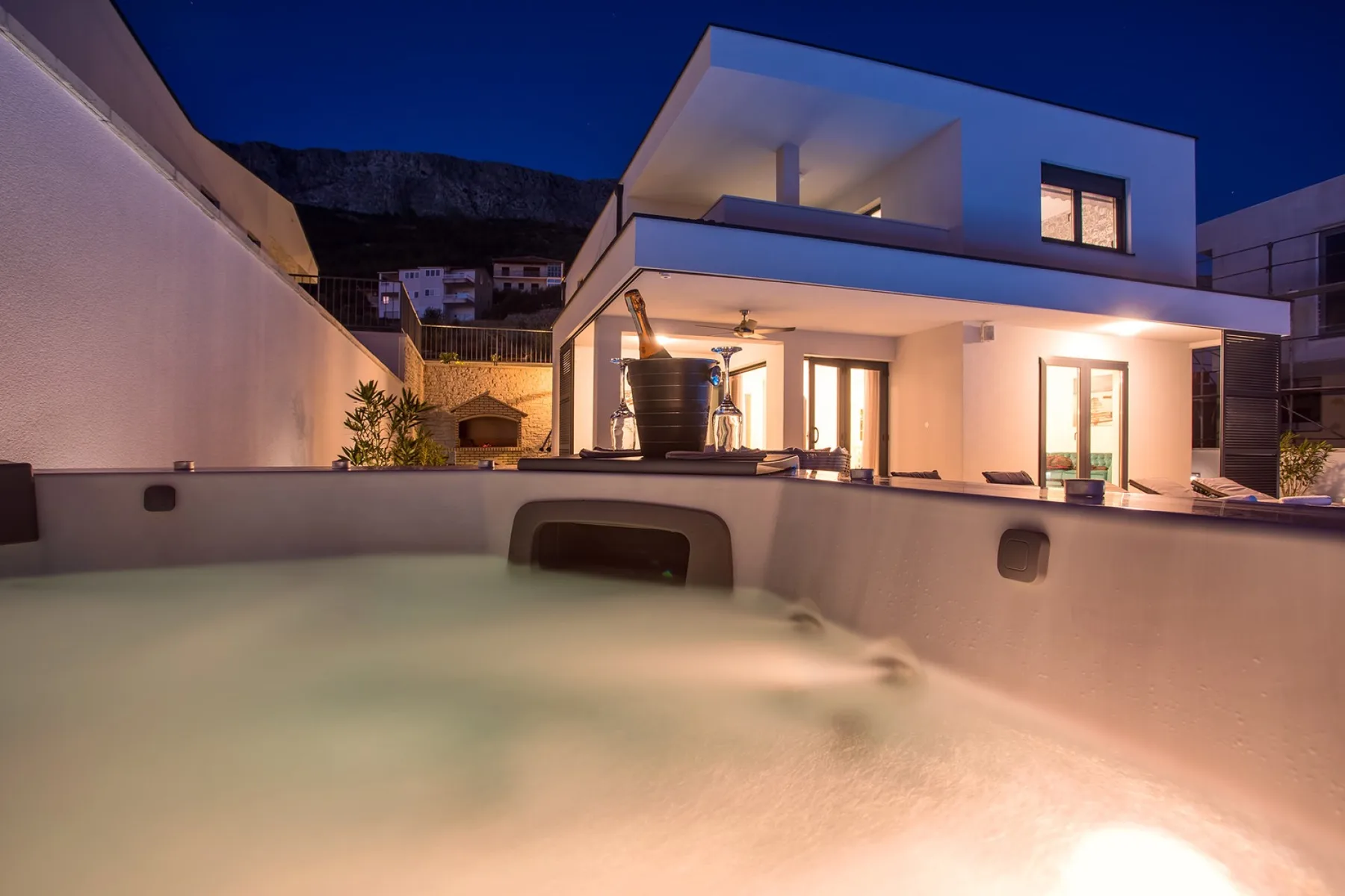 A modern house glows at dusk beside a swimming pool.