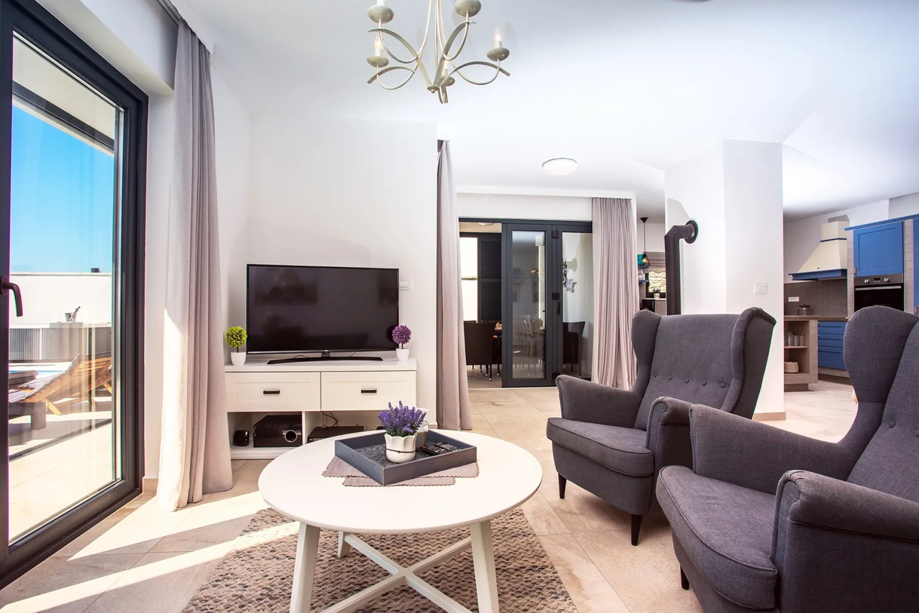 A bright living room with armchairs, a coffee table, and a television.