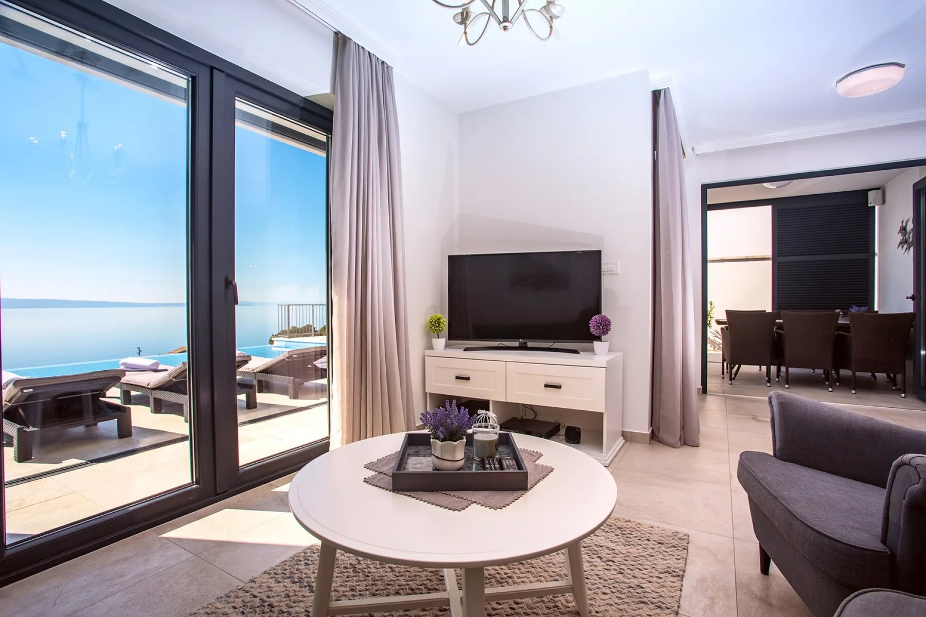 A bright living room with a television and glass doors opening onto a balcony.