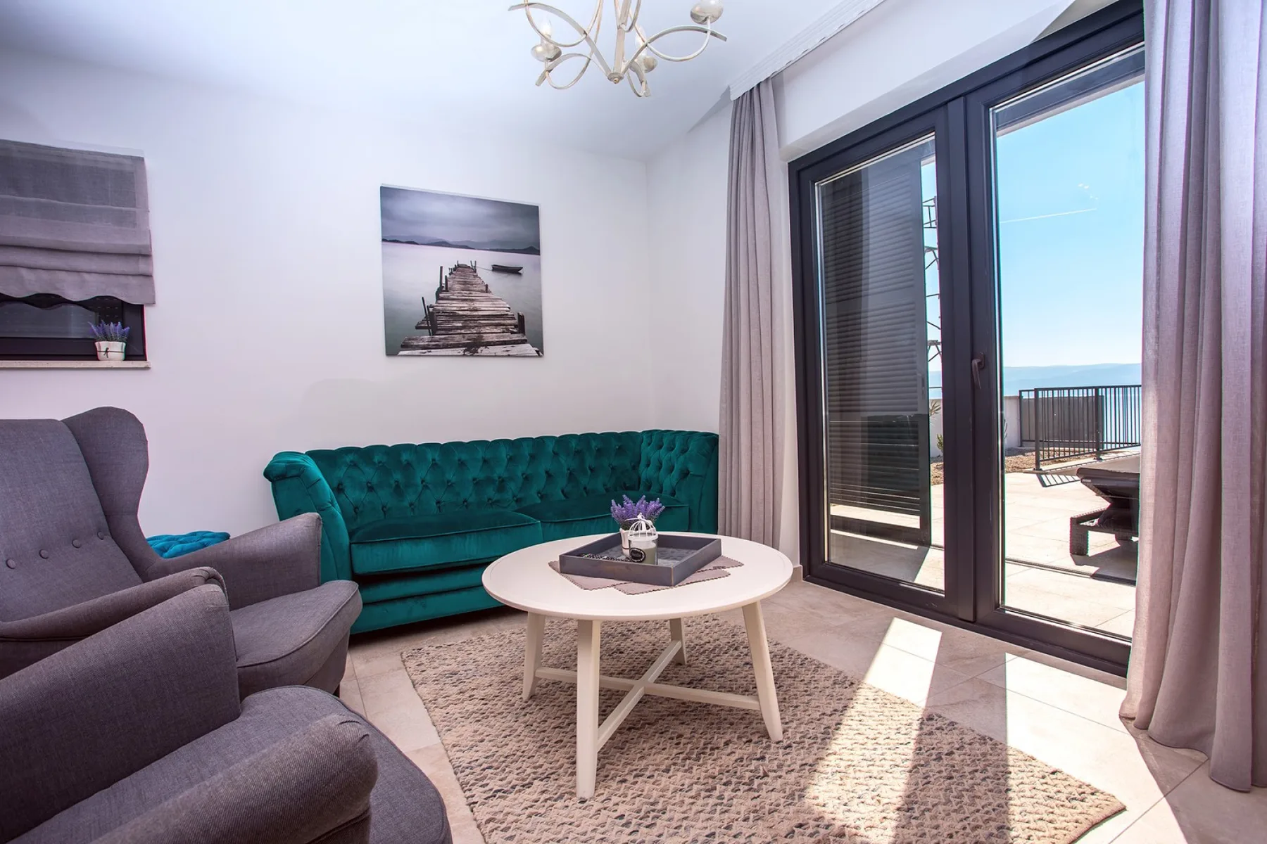 A bright living room with seating, a round coffee table, and glass doors to a balcony.