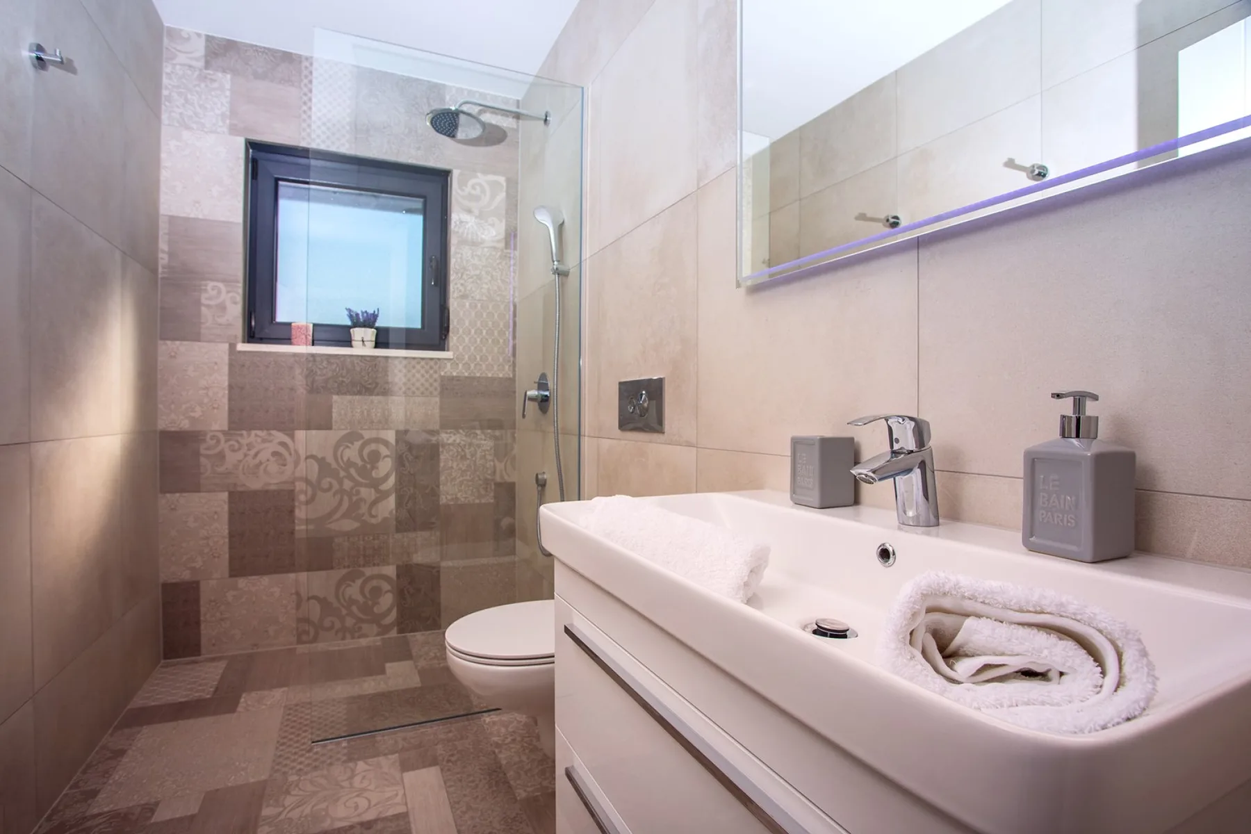 A tiled bathroom with a shower, toilet, and sink.