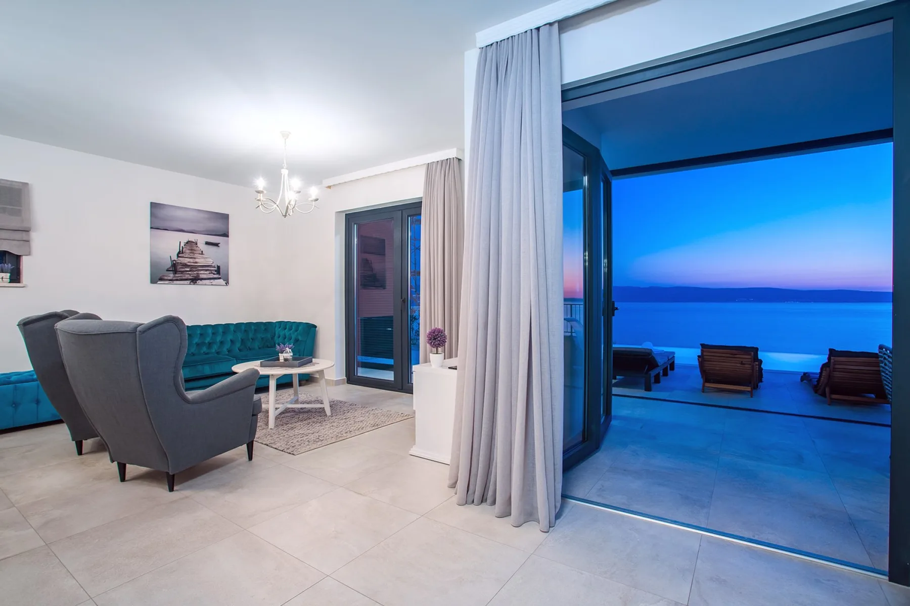 A living room opens onto a terrace with seating and a view of the water.