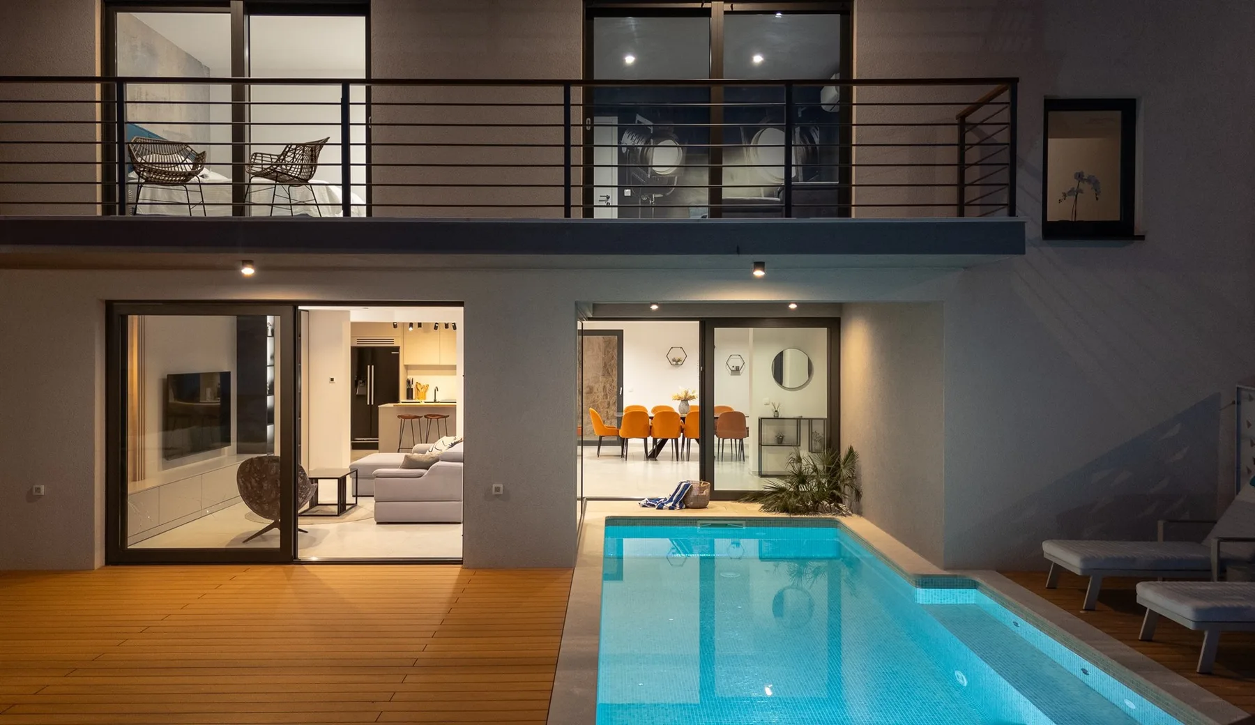 A modern interior opens onto a swimming pool and wooden deck.