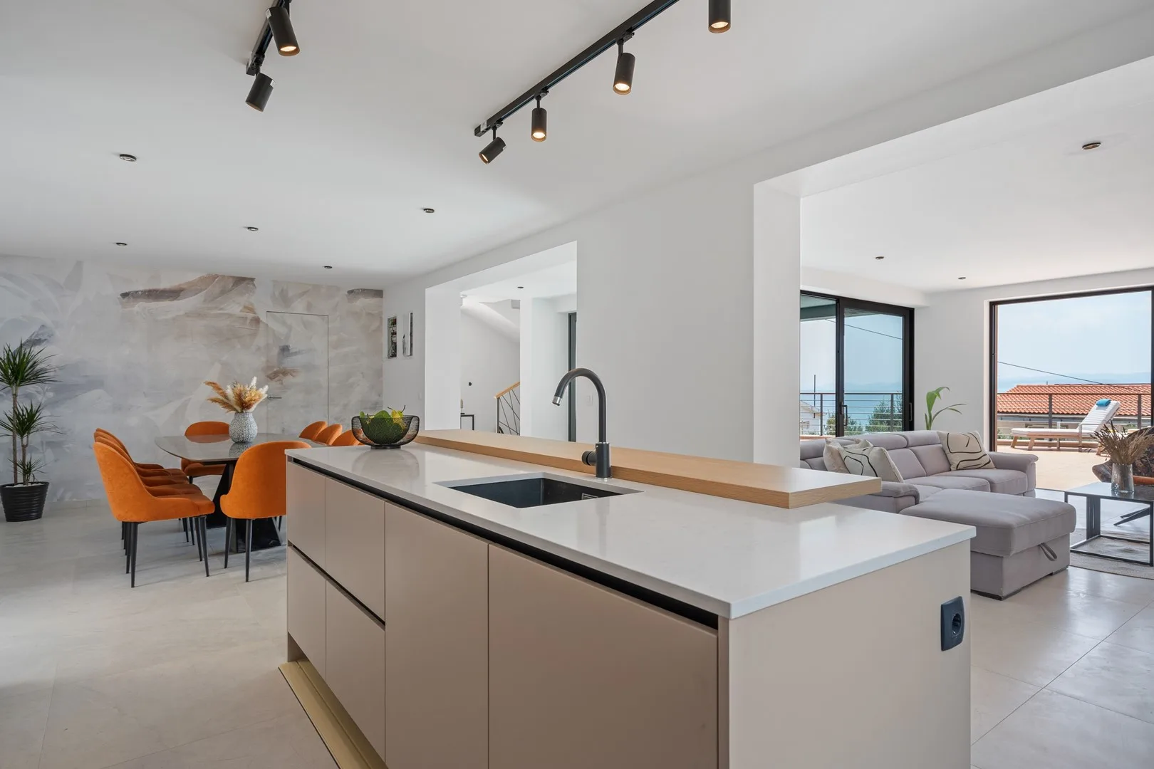 An open-plan kitchen and living area with a dining table and large windows.
