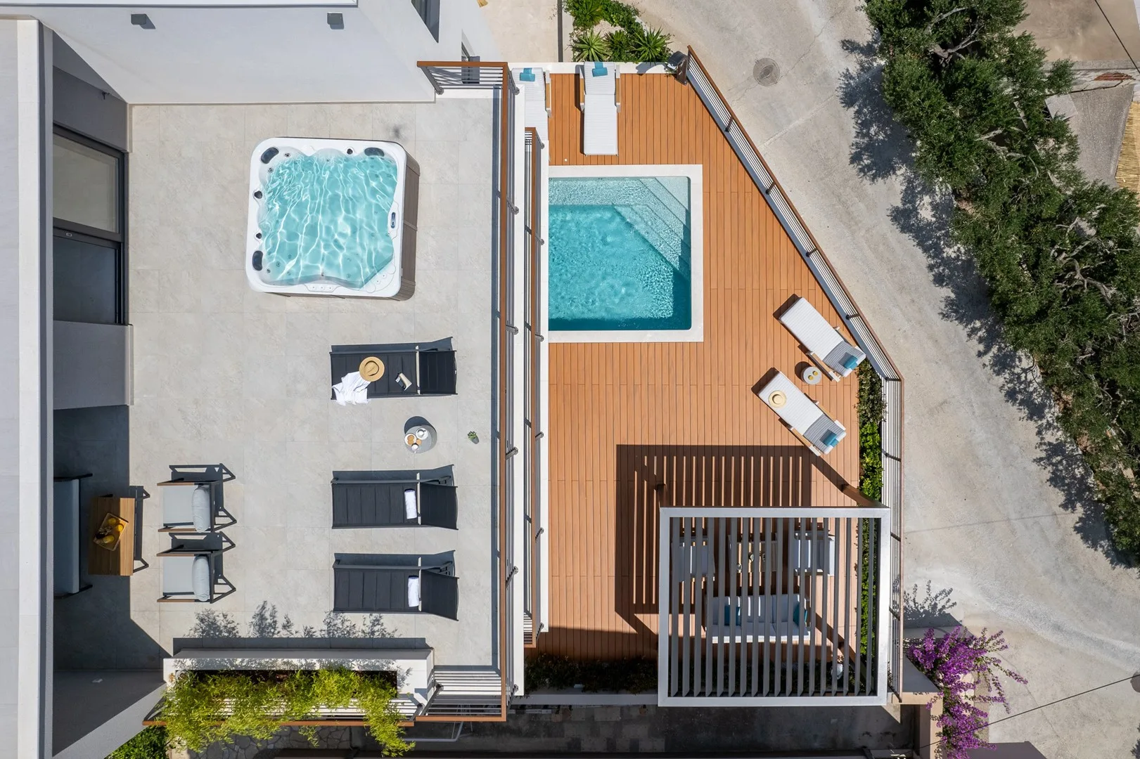 An overhead view of a rooftop pool and deck beside a smaller hot tub.