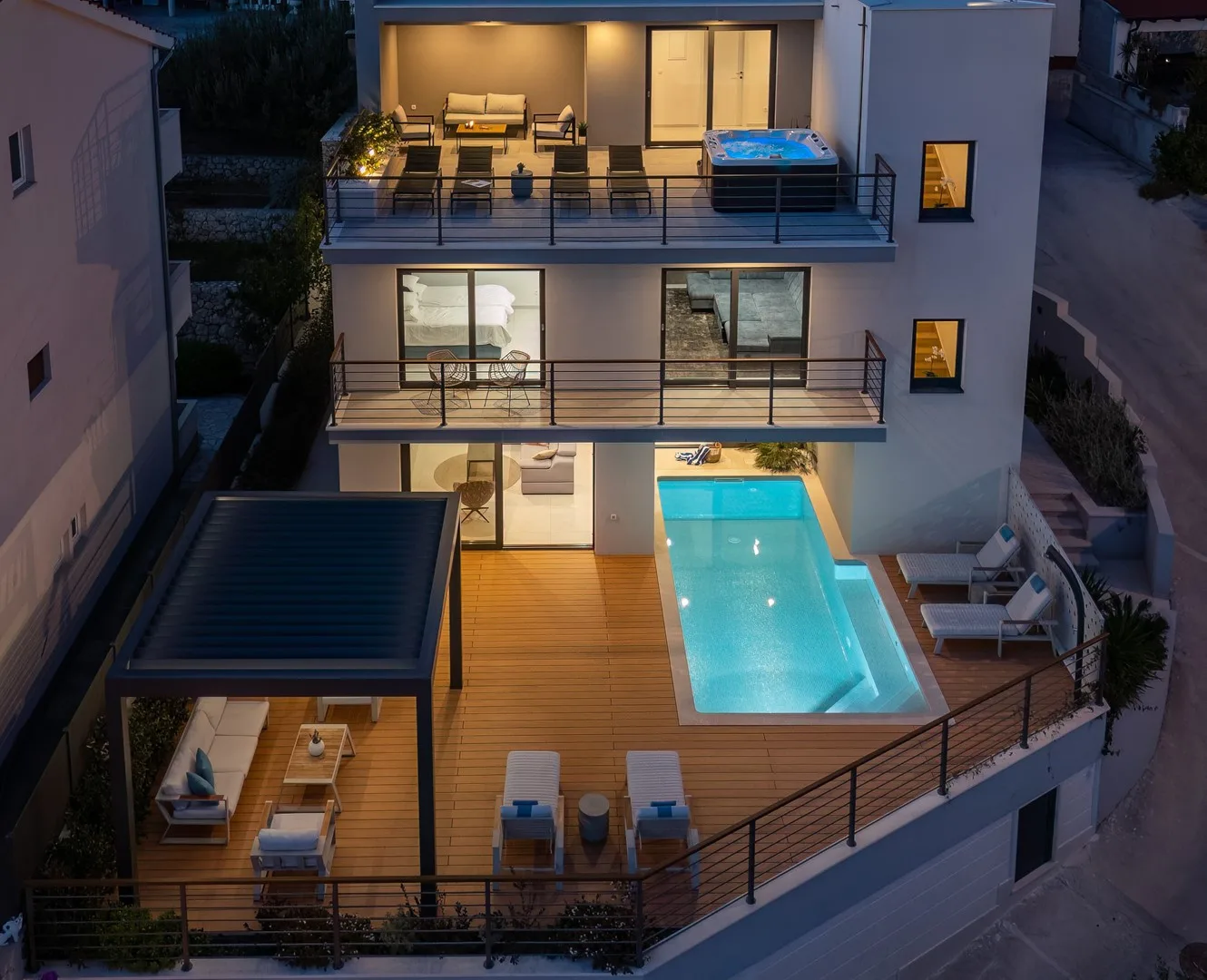 A modern multi-story house with balconies, outdoor seating, and a swimming pool.