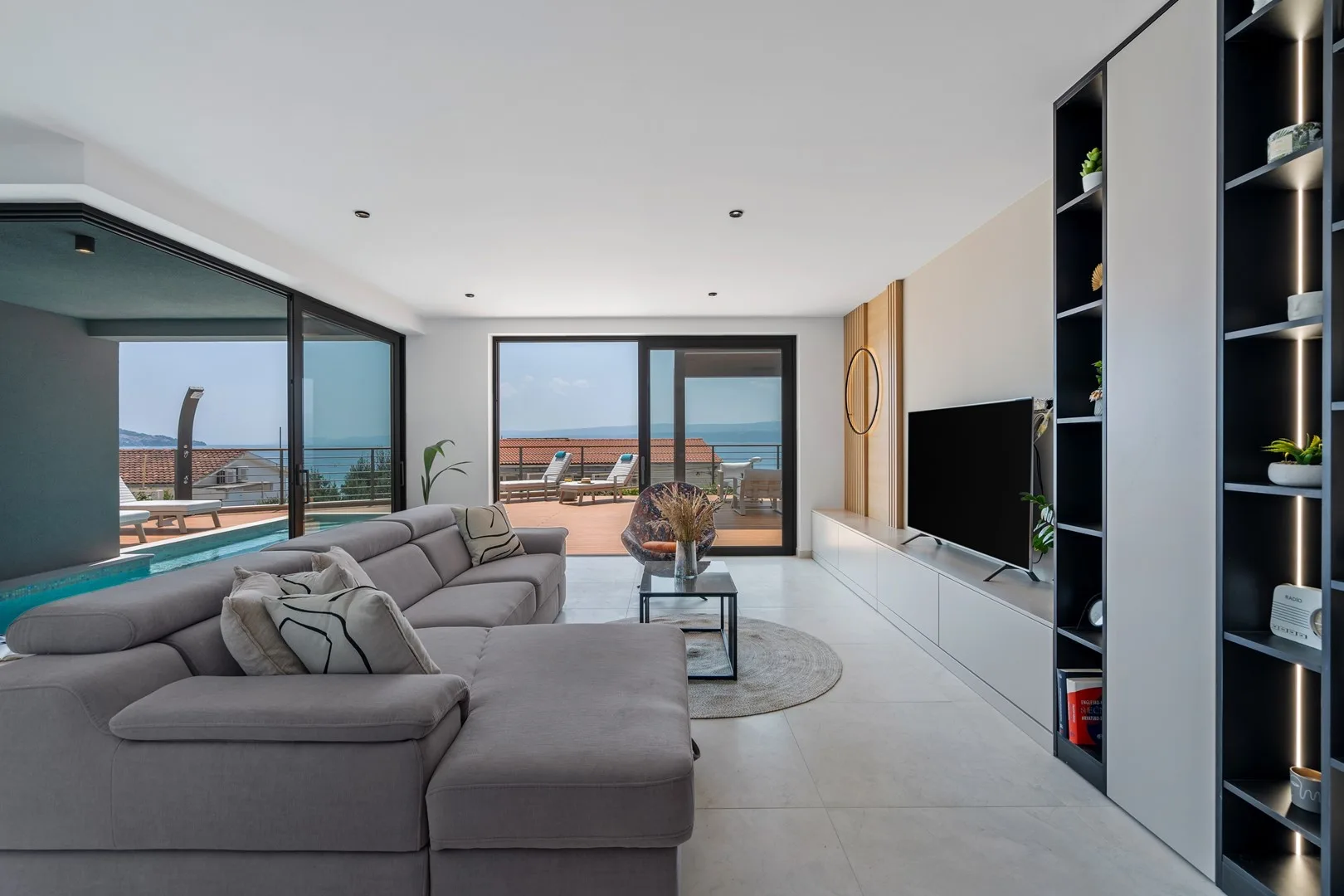 A bright living room with gray seating and sliding glass doors opening onto a terrace.